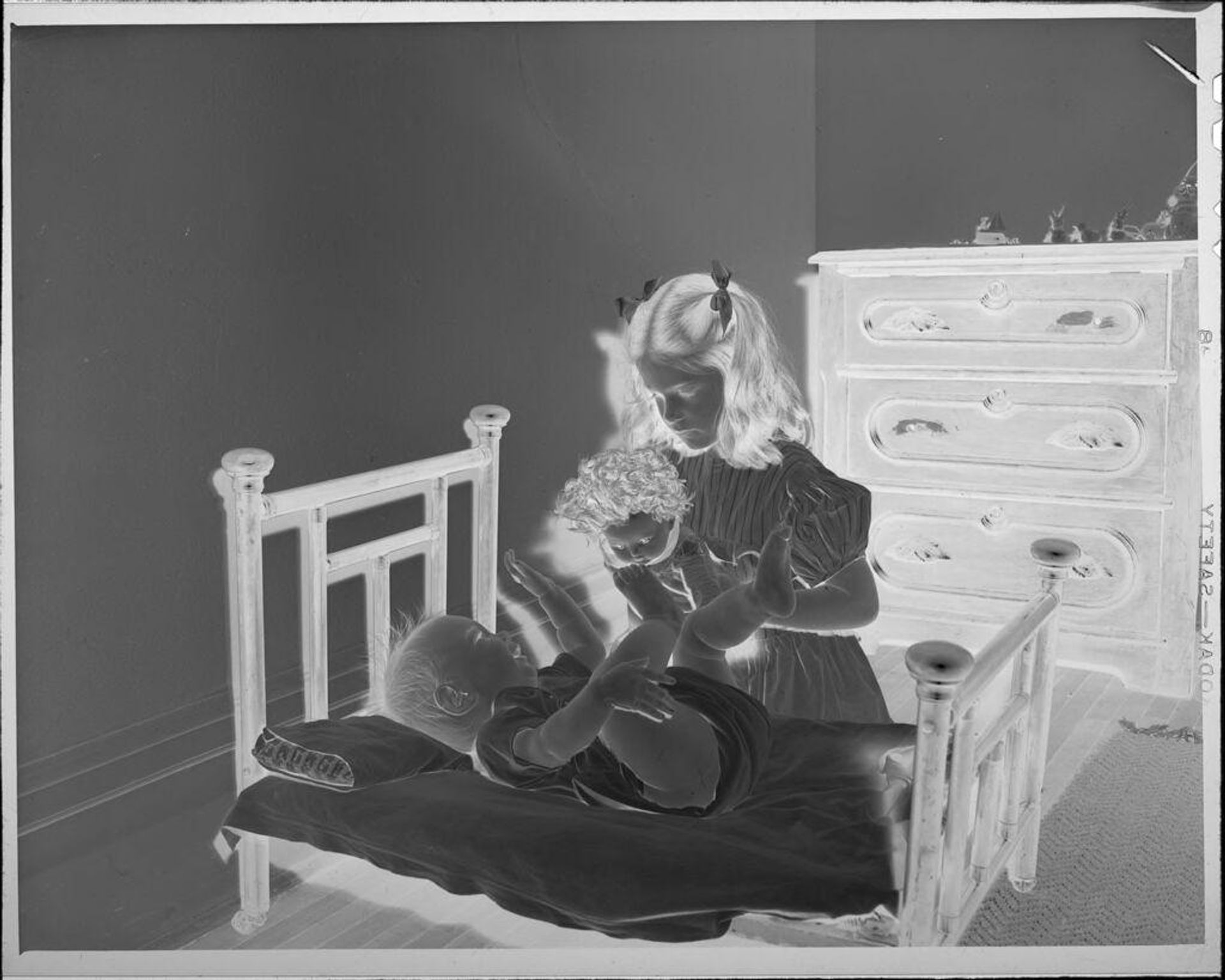 Untitled (girl with doll and baby on bed) by Lucian and Mary Brown