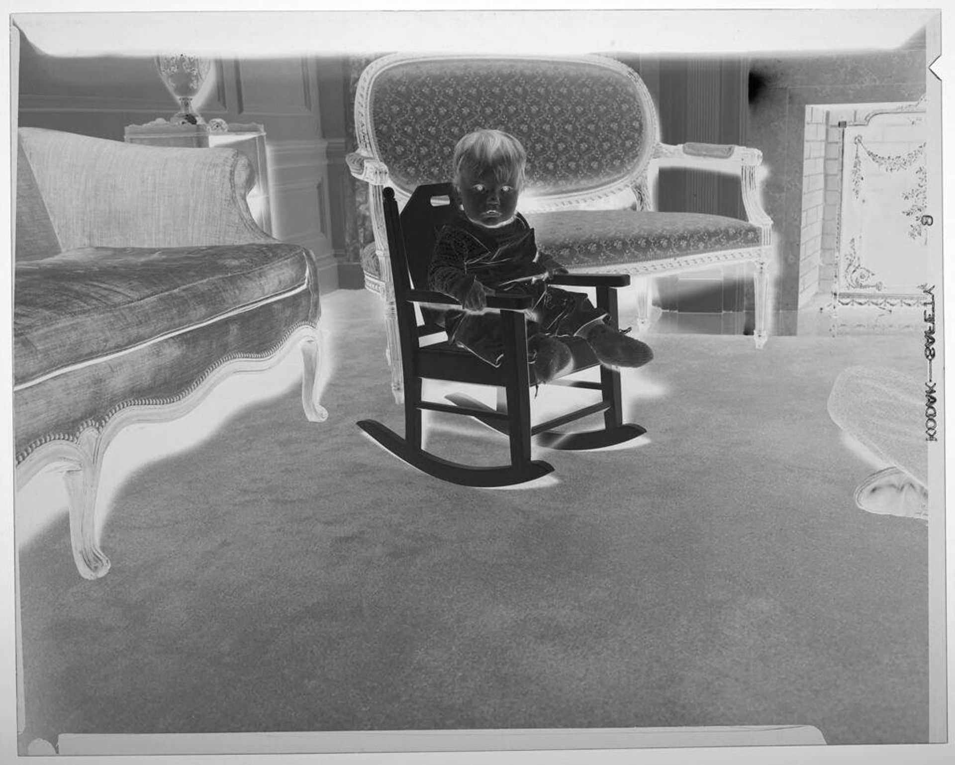 Untitled (baby posed sitting in rocking chair living room) by Martin Schweig