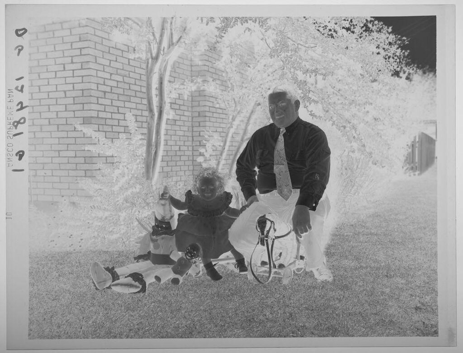 Untitled (father and daugher on lawn with toy dolls and hobby horse) by Paul Gittings