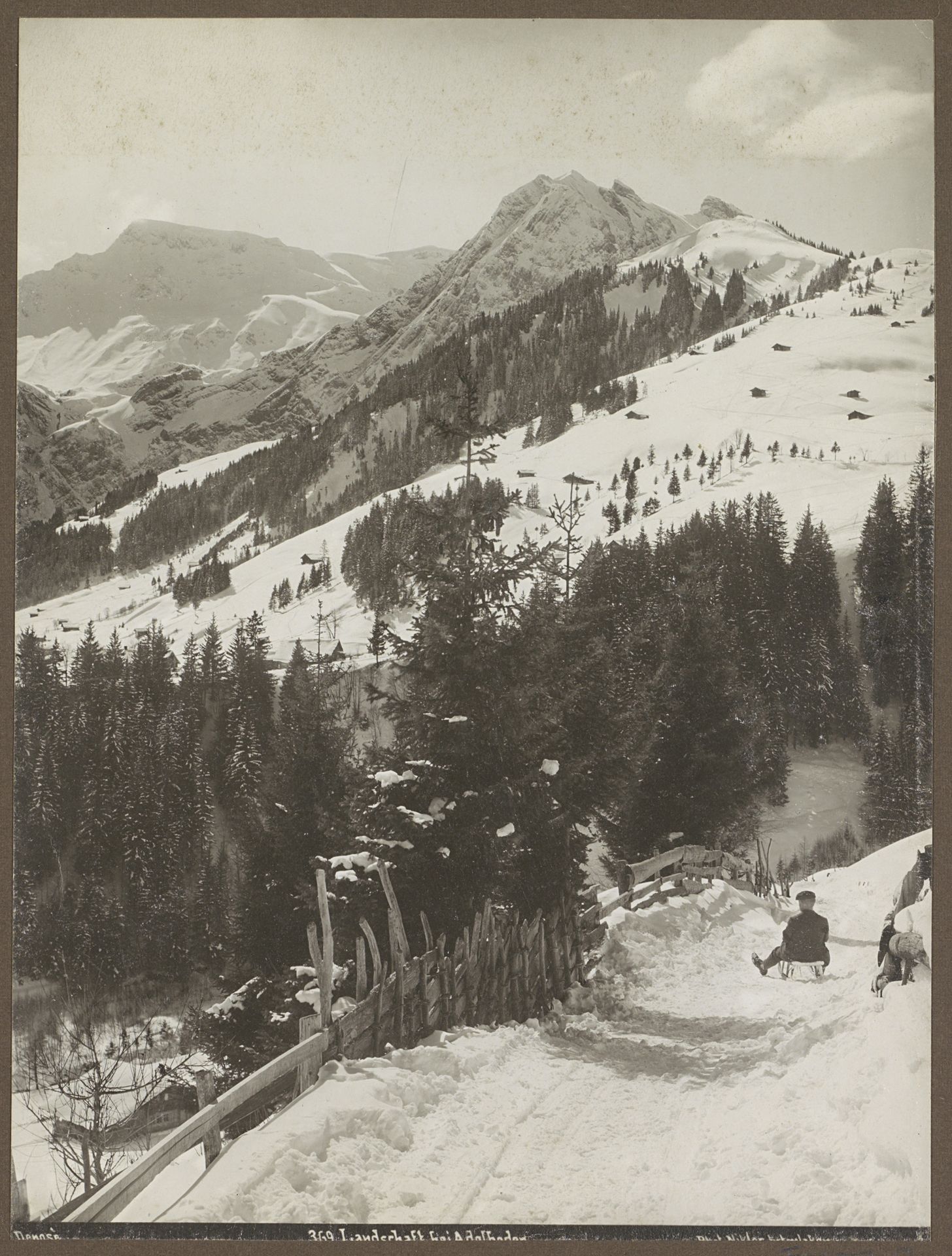 Gezicht op de besneeuwde berghellingen van Adelboden met rechts een man op een slee by Nikles