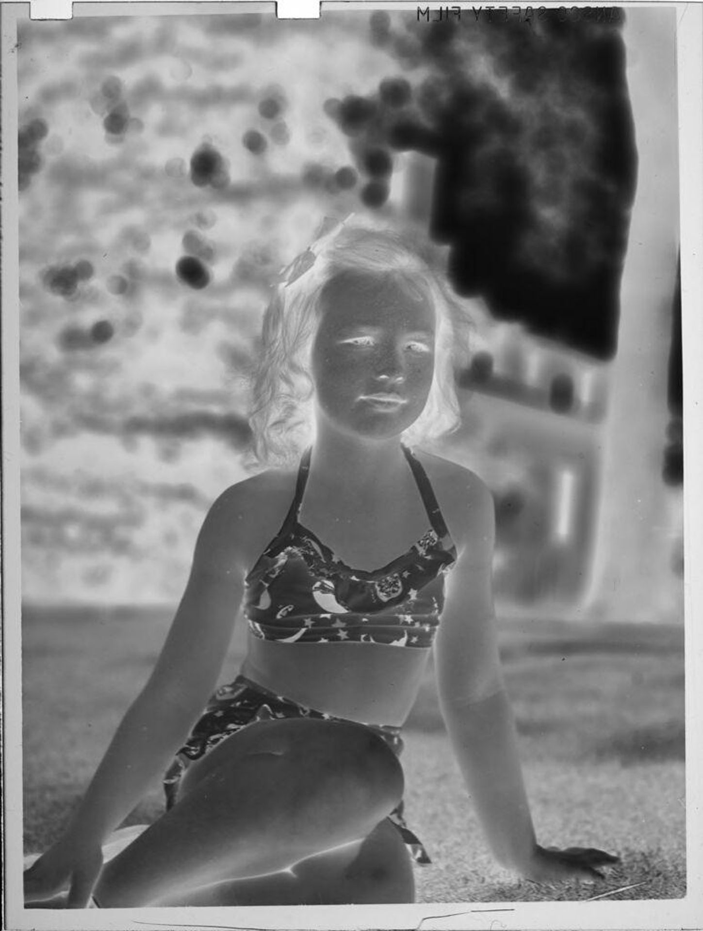 Untitled (girl wearing bikini, sitting outside house) by Lucian and Mary Brown