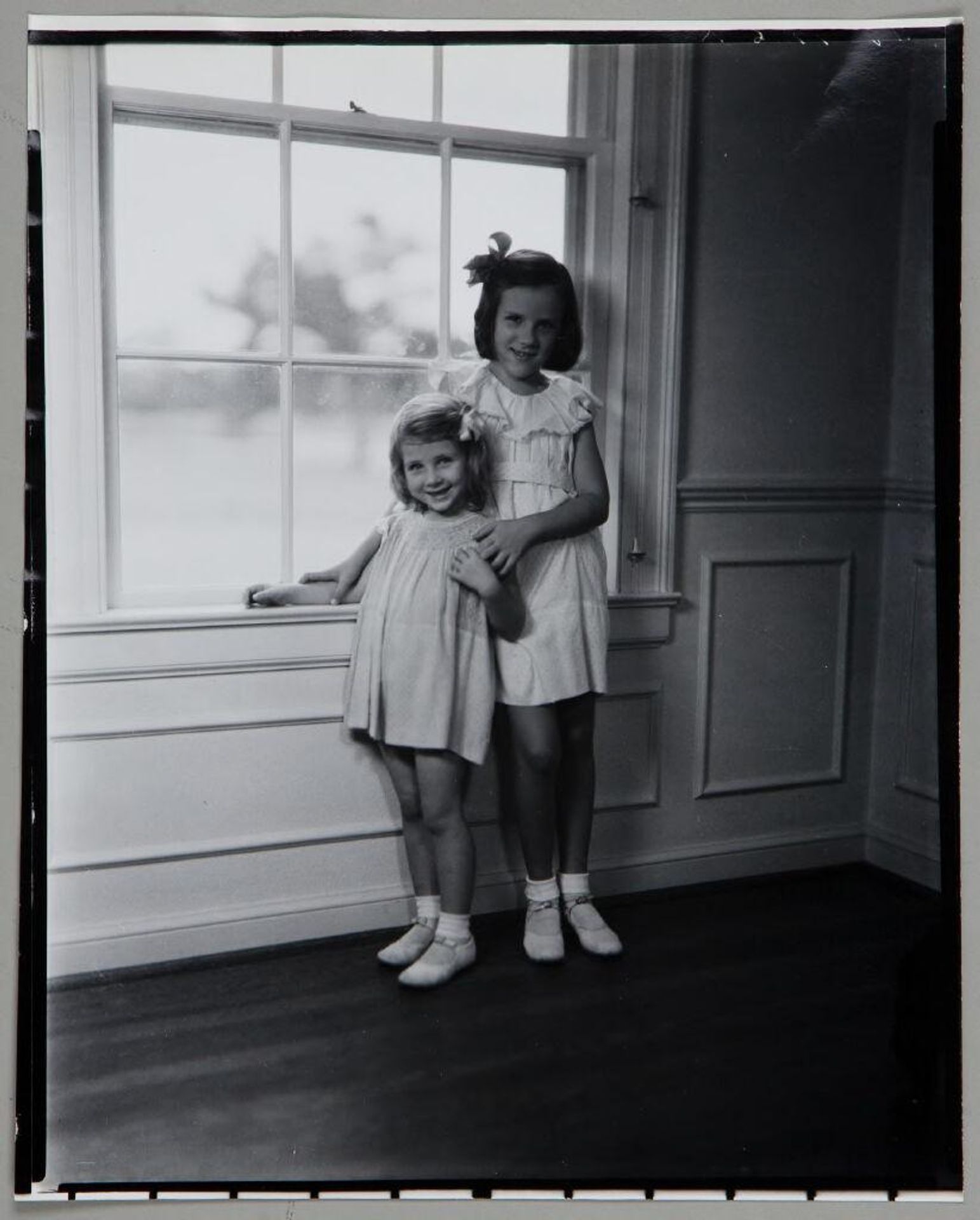Untitled (two girls standing together in front of window) by Paul Gittings