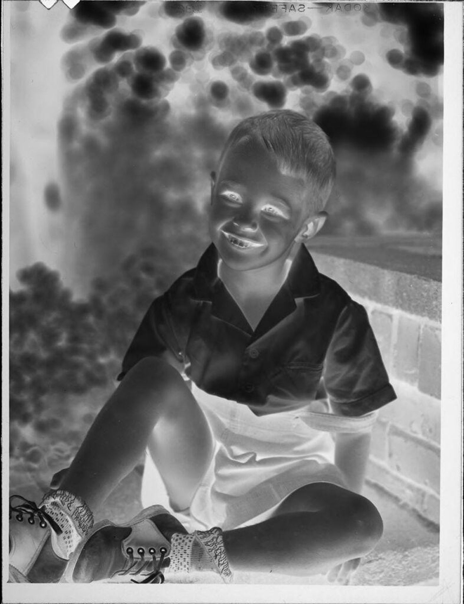 Untitled (little boy sitting on brick wall) by Lucian and Mary Brown