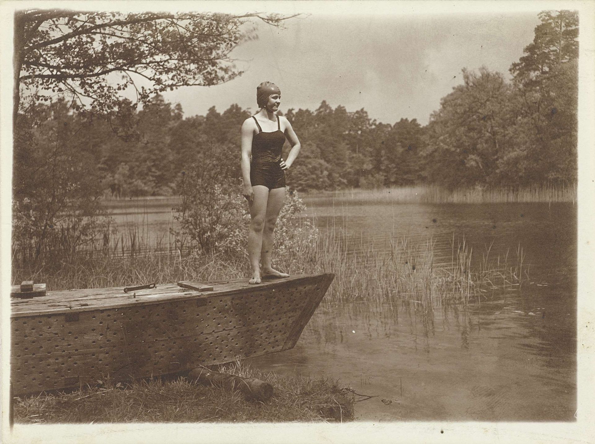 Onbekende jonge vrouw in badpak op een roeiboot aan de rand van een meer by Waldemar Titzenthaler