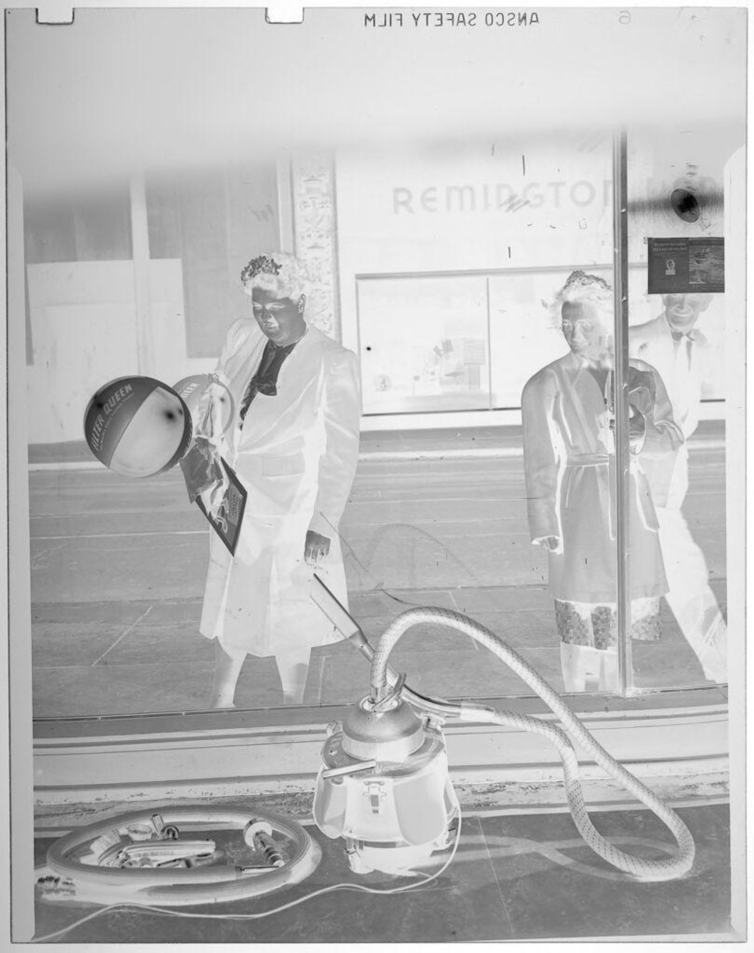Untitled (men looking at vacuum demonstration in shop window) by Jack Gould
