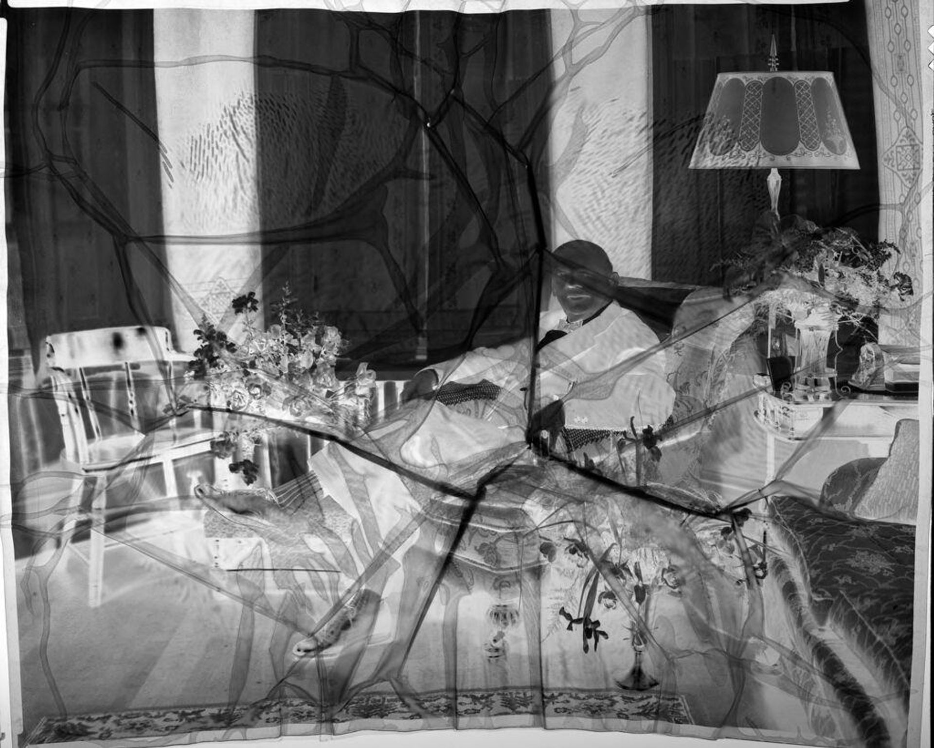 Untitled (man sitting in chair with flowers around) by Hamblin Studio