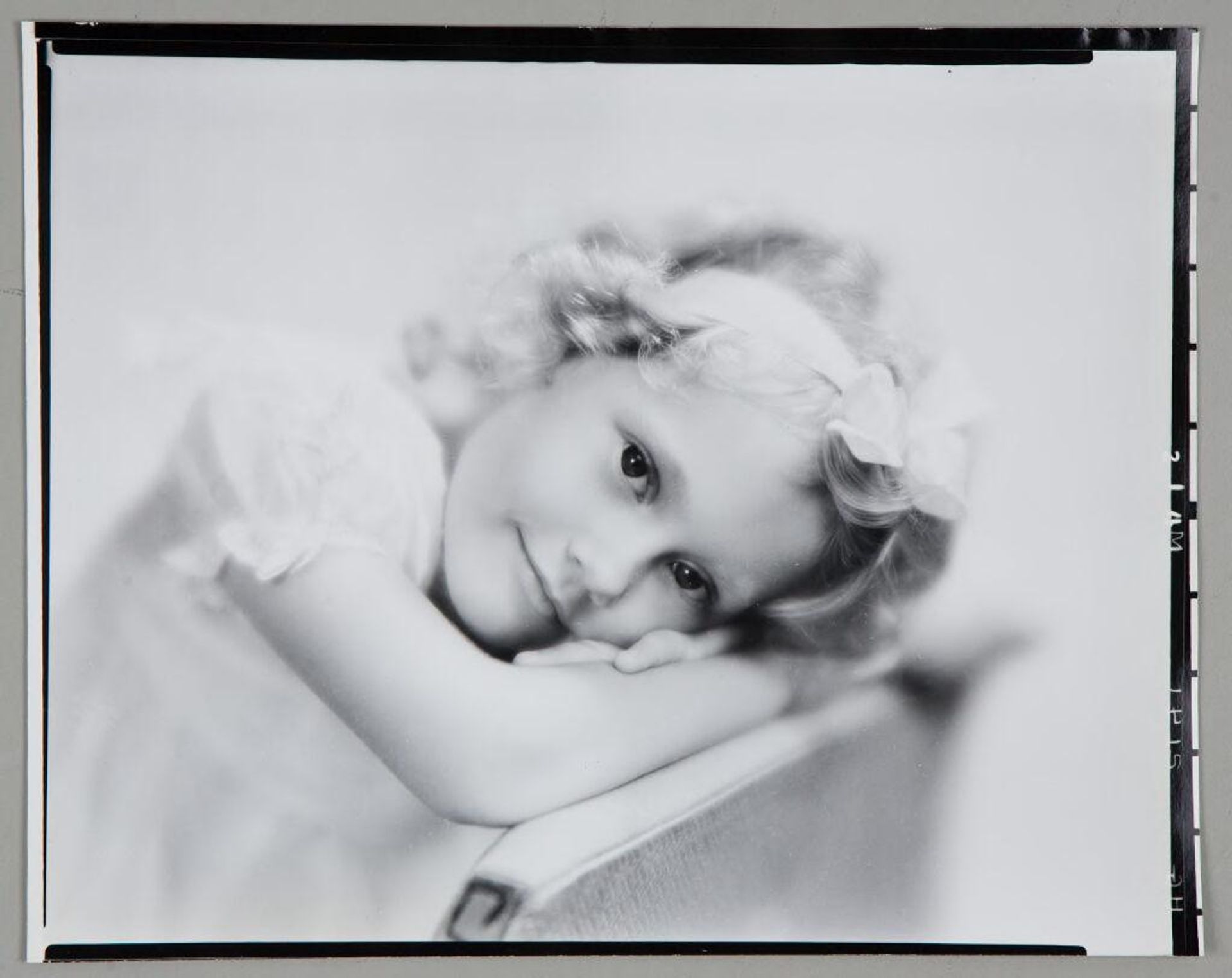 Untitled (portrait of blond girl with bow in hair resting head and arms on back of chair) by Paul Gittings