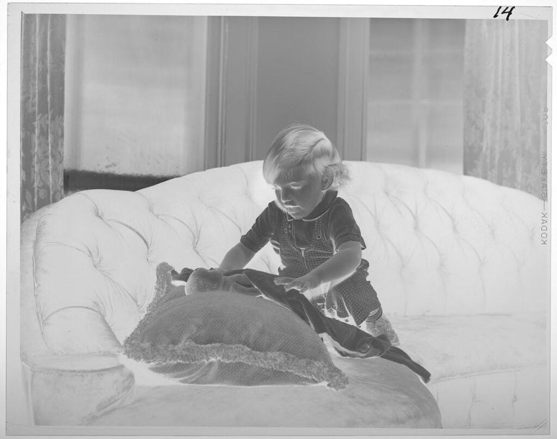 Untitled (child playing with doll on couch) by Lucian and Mary Brown