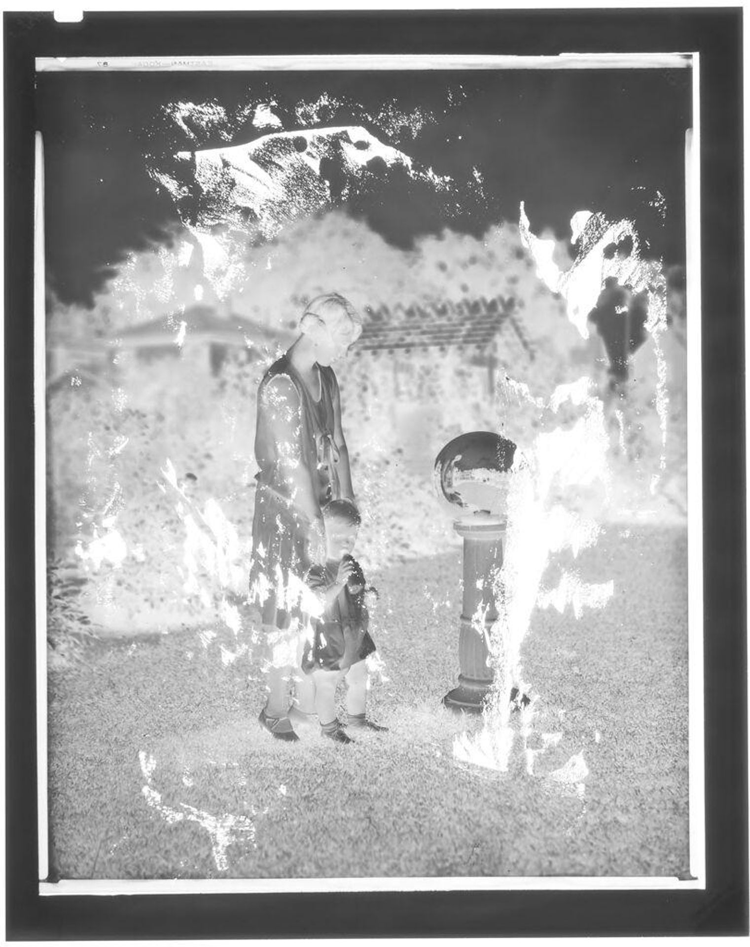 Untitled (mother and daughter by reflecting ball in garden) by Hamblin Studio