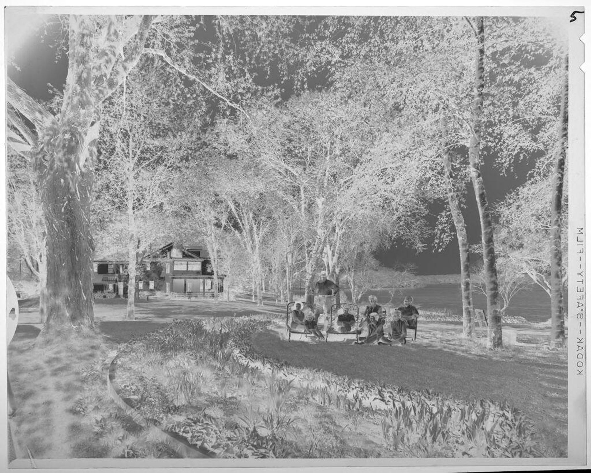 Untitled (family sitting on large lawn in front of house by river) by Lucian and Mary Brown