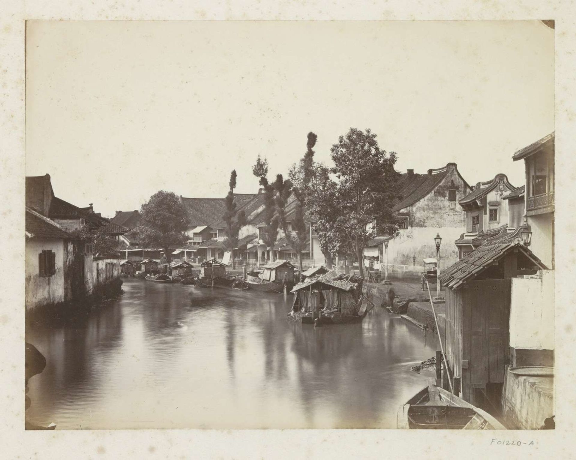 Gezicht op een rivierkade met huizen en boten op Java by Woodbury & Page