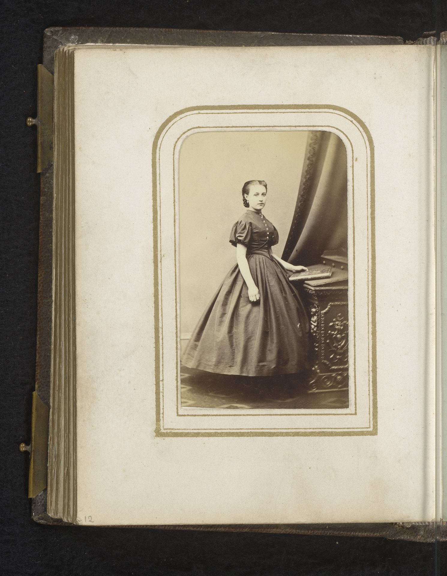 Portret van een jonge vrouw, staand bij een meubel met daarop een boek by Edinburgh Photographic Gallery