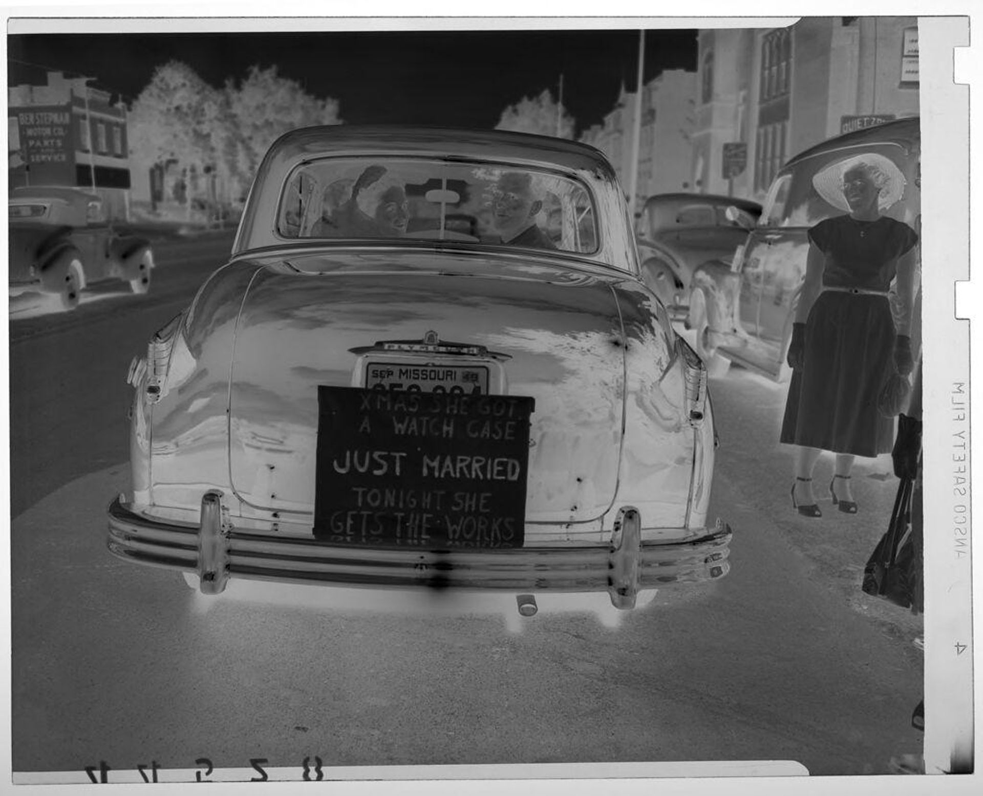 Untitled (bride and groom posing from back of wedding car as woman watches) by Martin Schweig