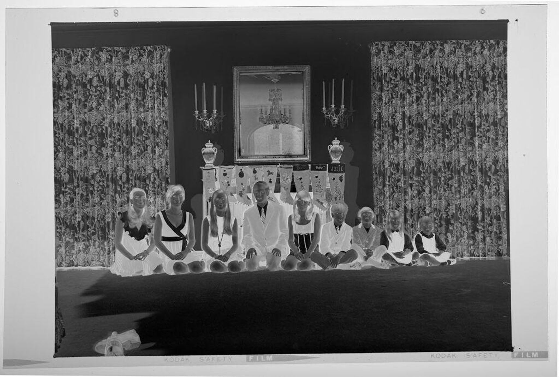 Untitled (nine children posed sitting in front of fireplace decorated for Christmas) by Martin Schweig