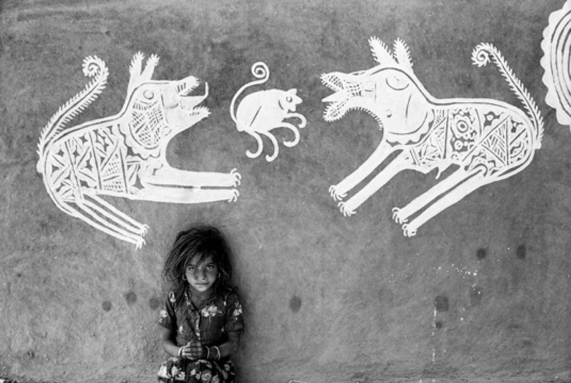 A young girl in front of mandana paintings, Rajasthan by Jyoti Bhatt