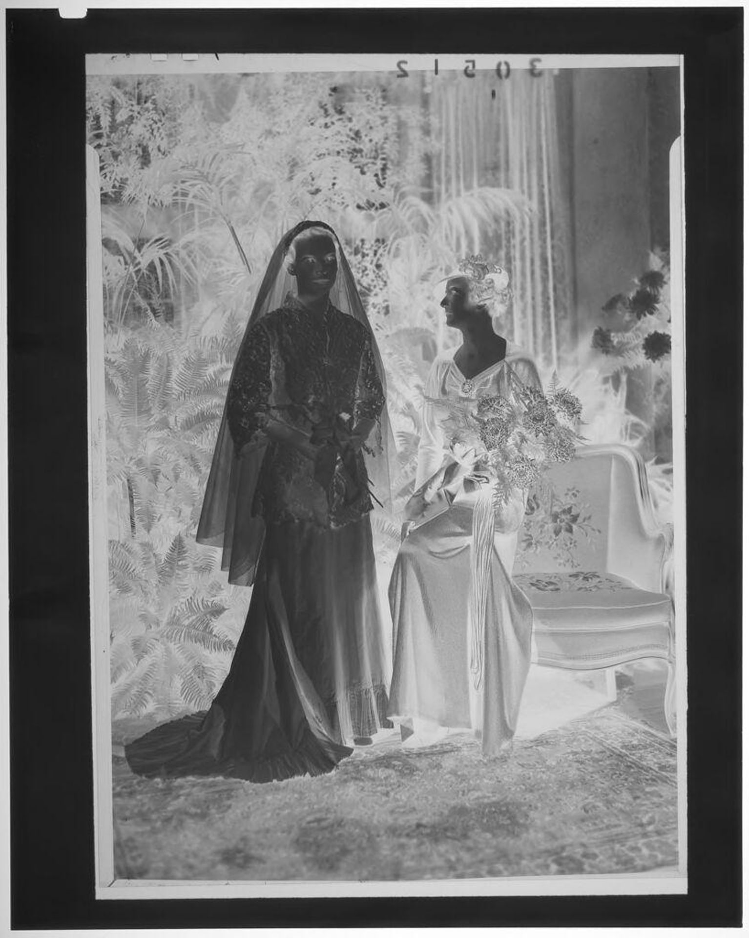 Untitled (portrait of bride with mother watching her in elegant room decorated with plants) by Martin Schweig