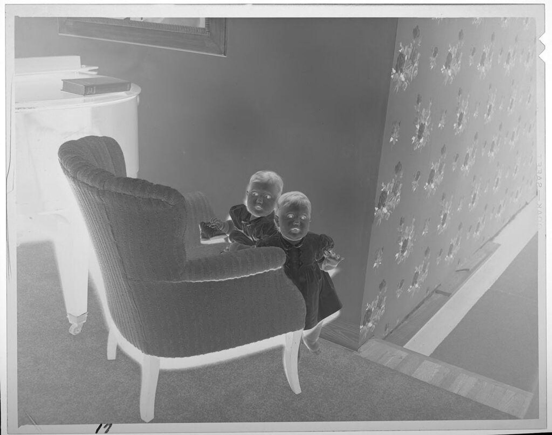Untitled (two toddlers in dresses standing behind armchair) by Lucian and Mary Brown