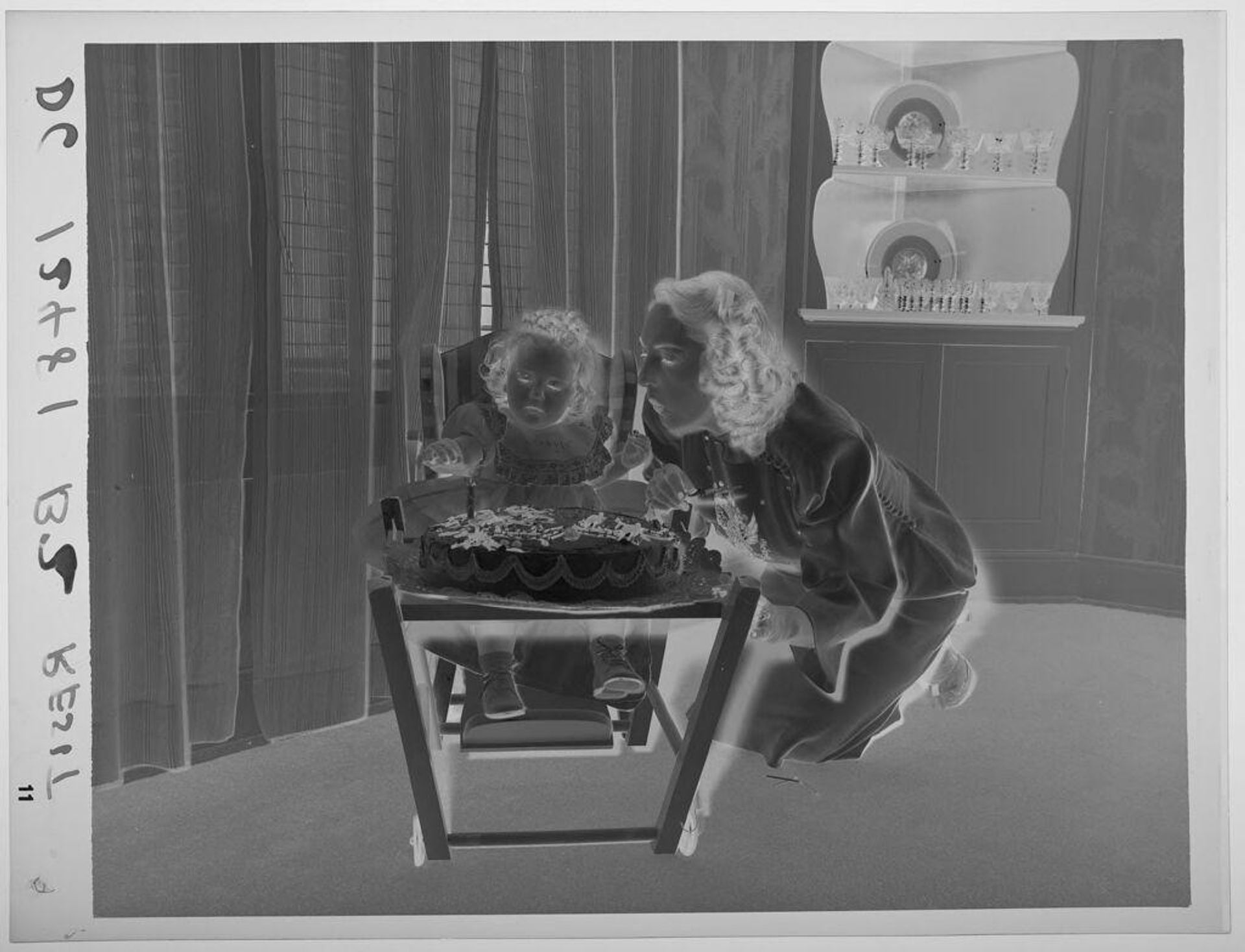 Untitled (mother leaning in to little girl and birthday cake, blowing on candle) by Paul Gittings