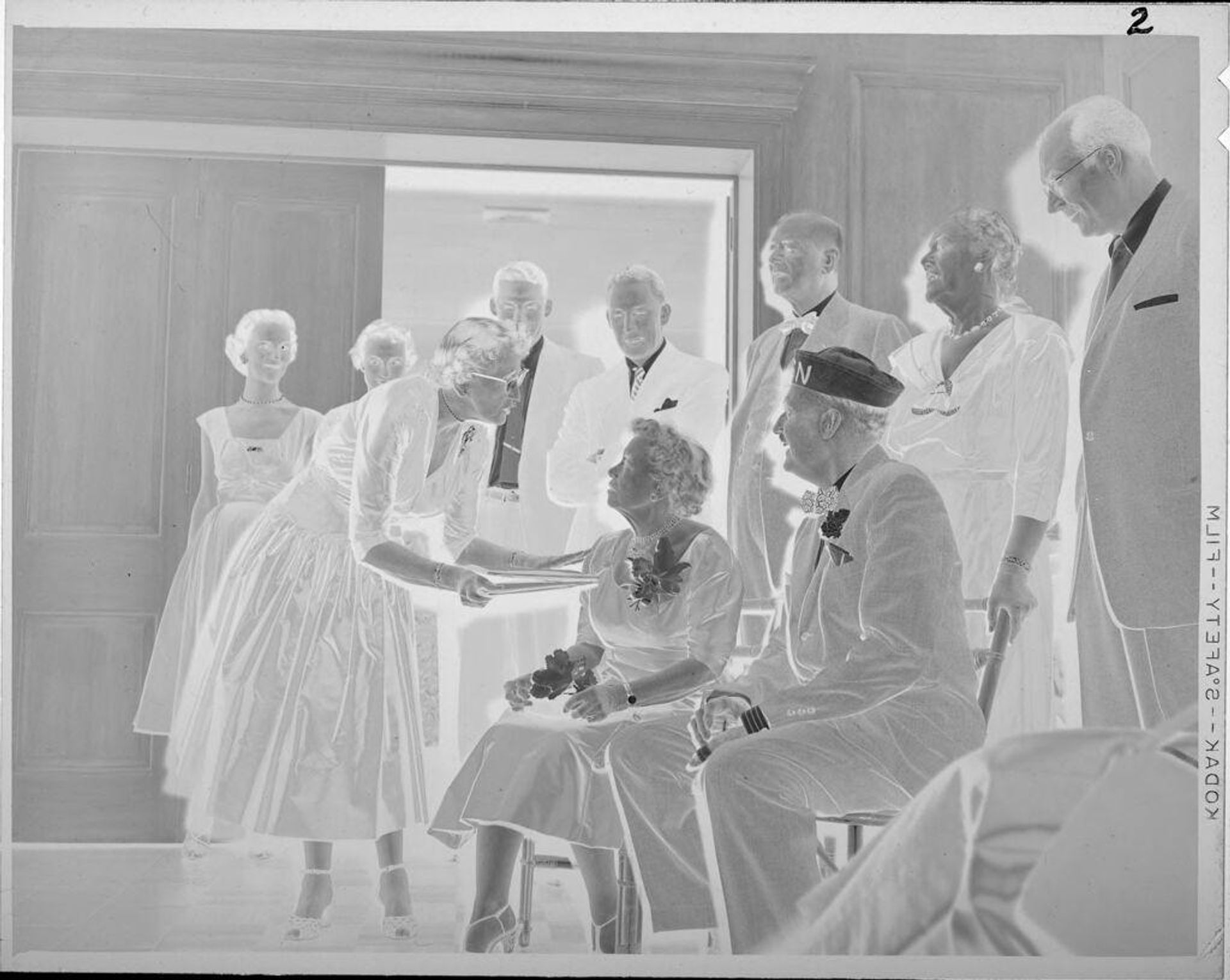Untitled (man and woman on chairs, people standing behind) by Lucian and Mary Brown