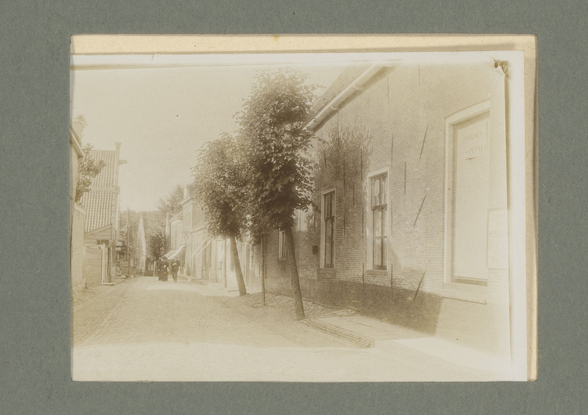 Straatbeeld met in de verte een man en vrouw by G. Hidderley