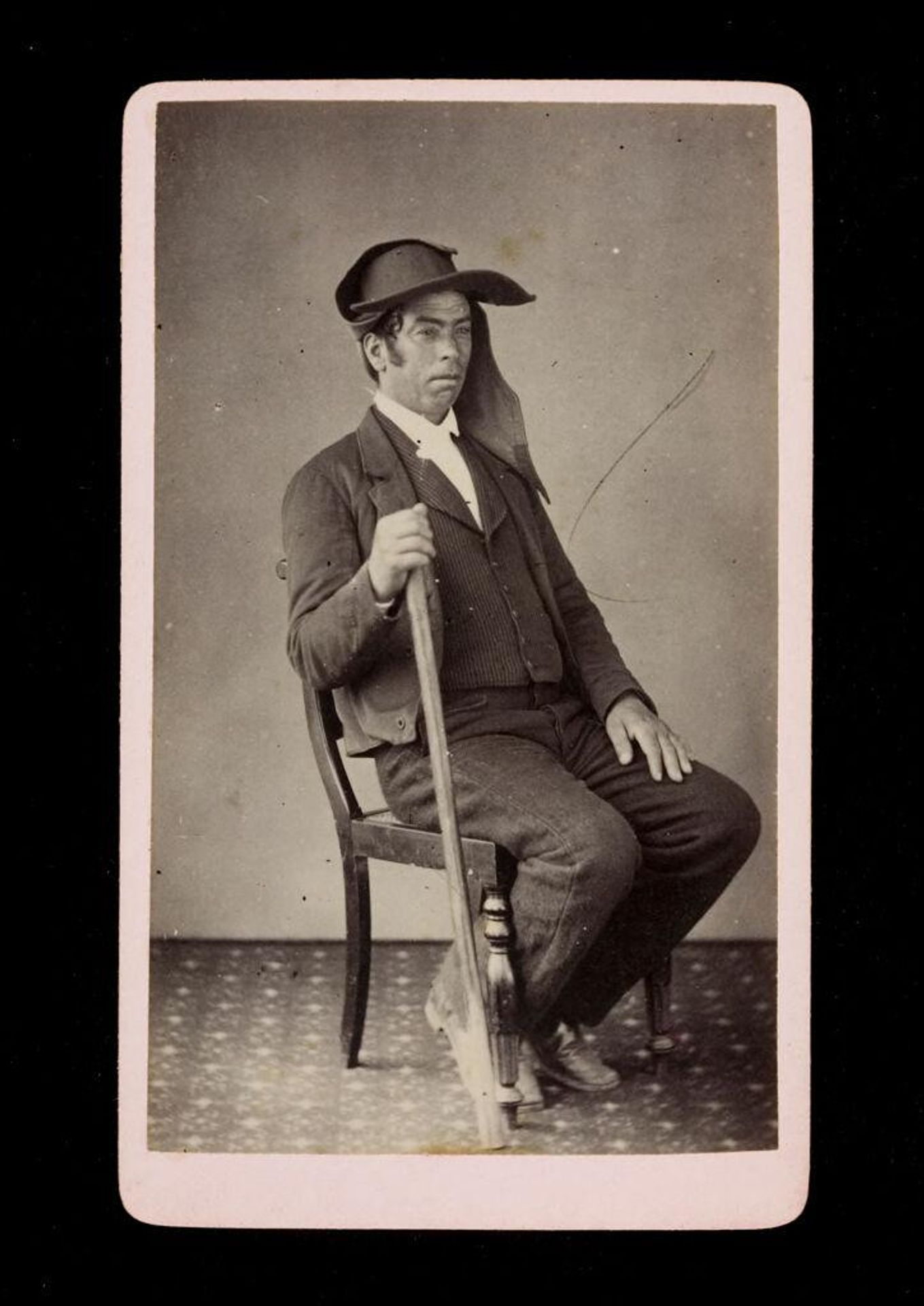 Costumes of Michaelenses, Azores, Portugal (man wearing hat, seated in chair, holding wooden stick) by A.J. Rapozo