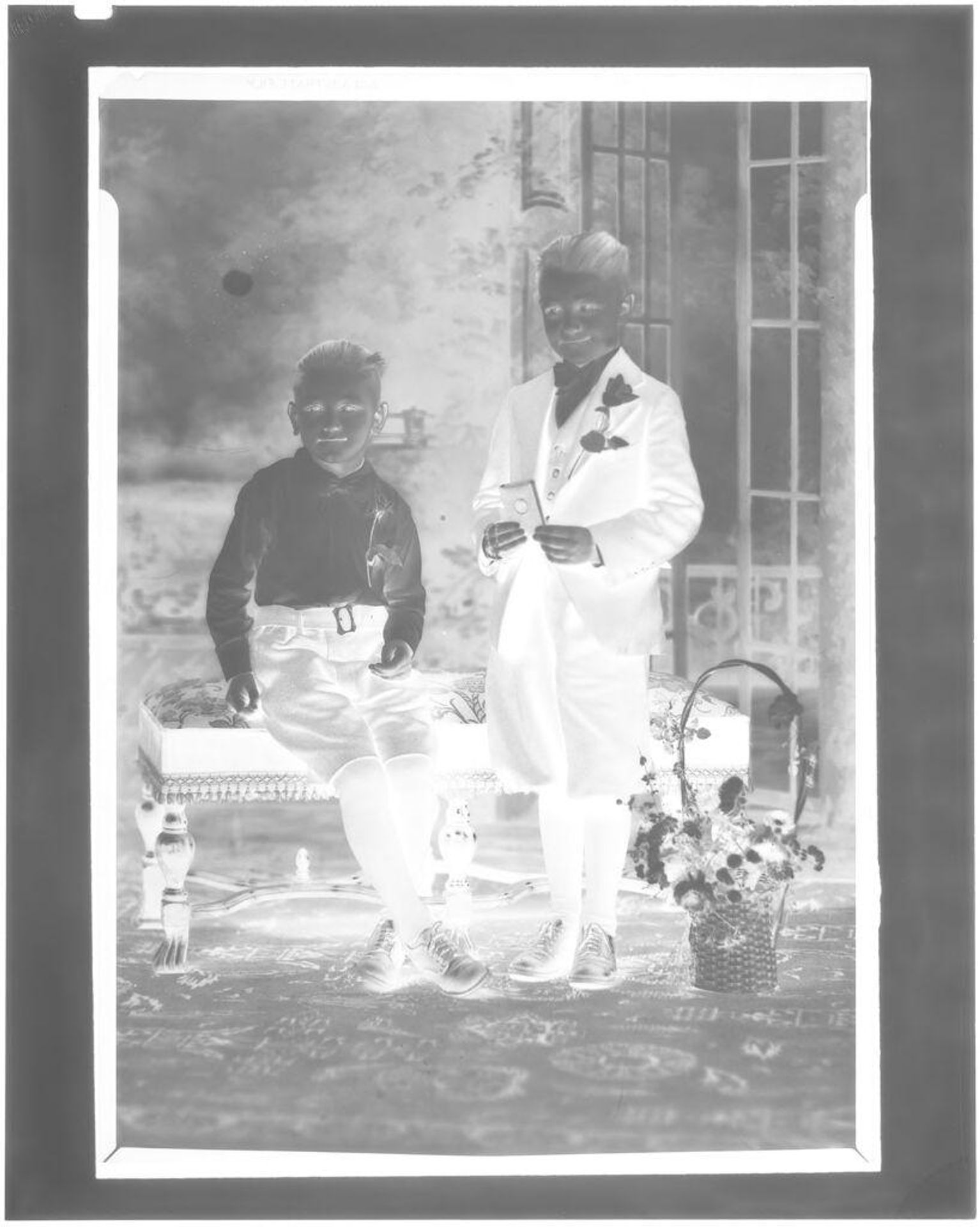 Untitled (two boys with roses on lapels seated on bench in studio) by John Deusing