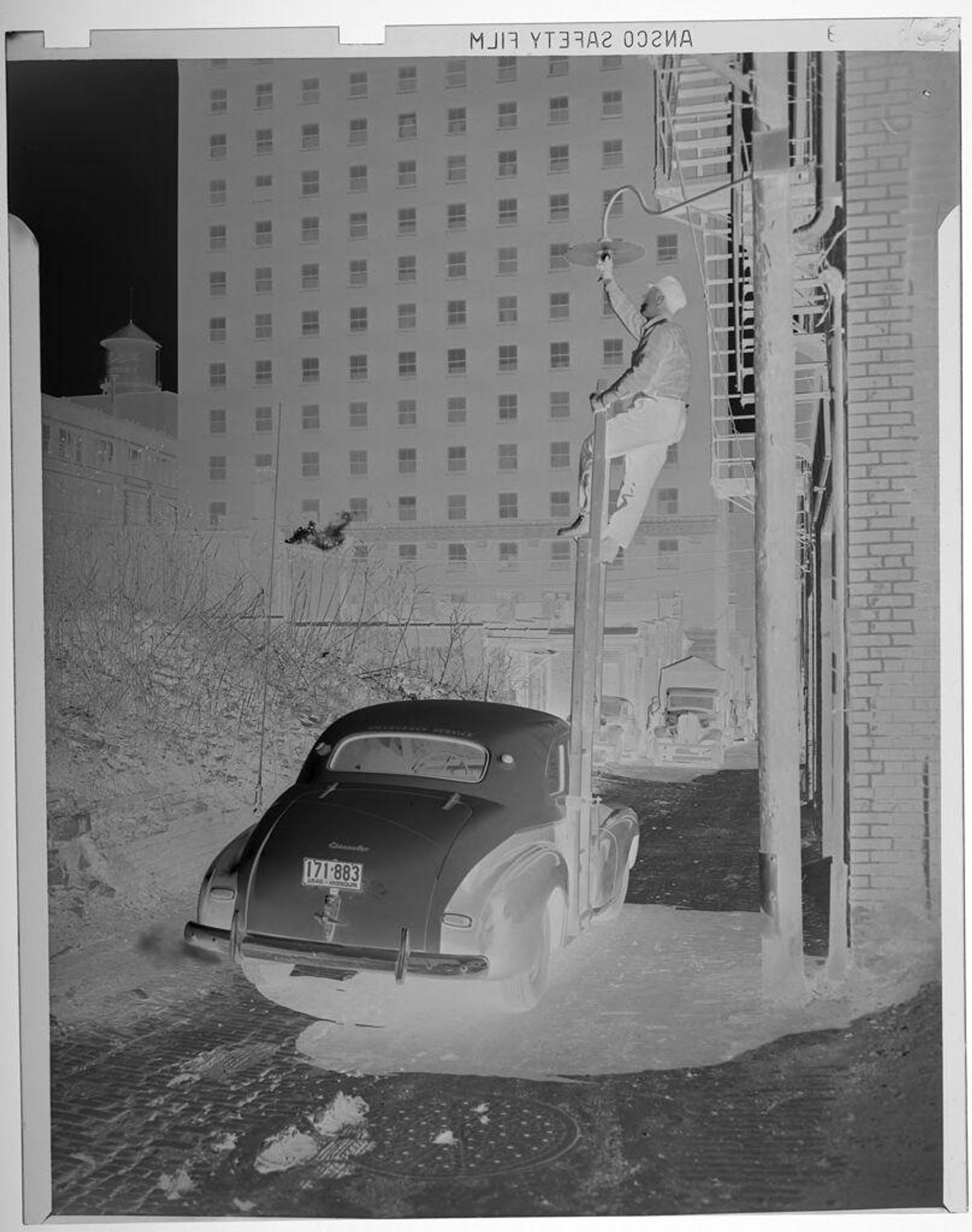 Untitled (man climbing up pole to fix light bulb on street lamp) by Jack Gould