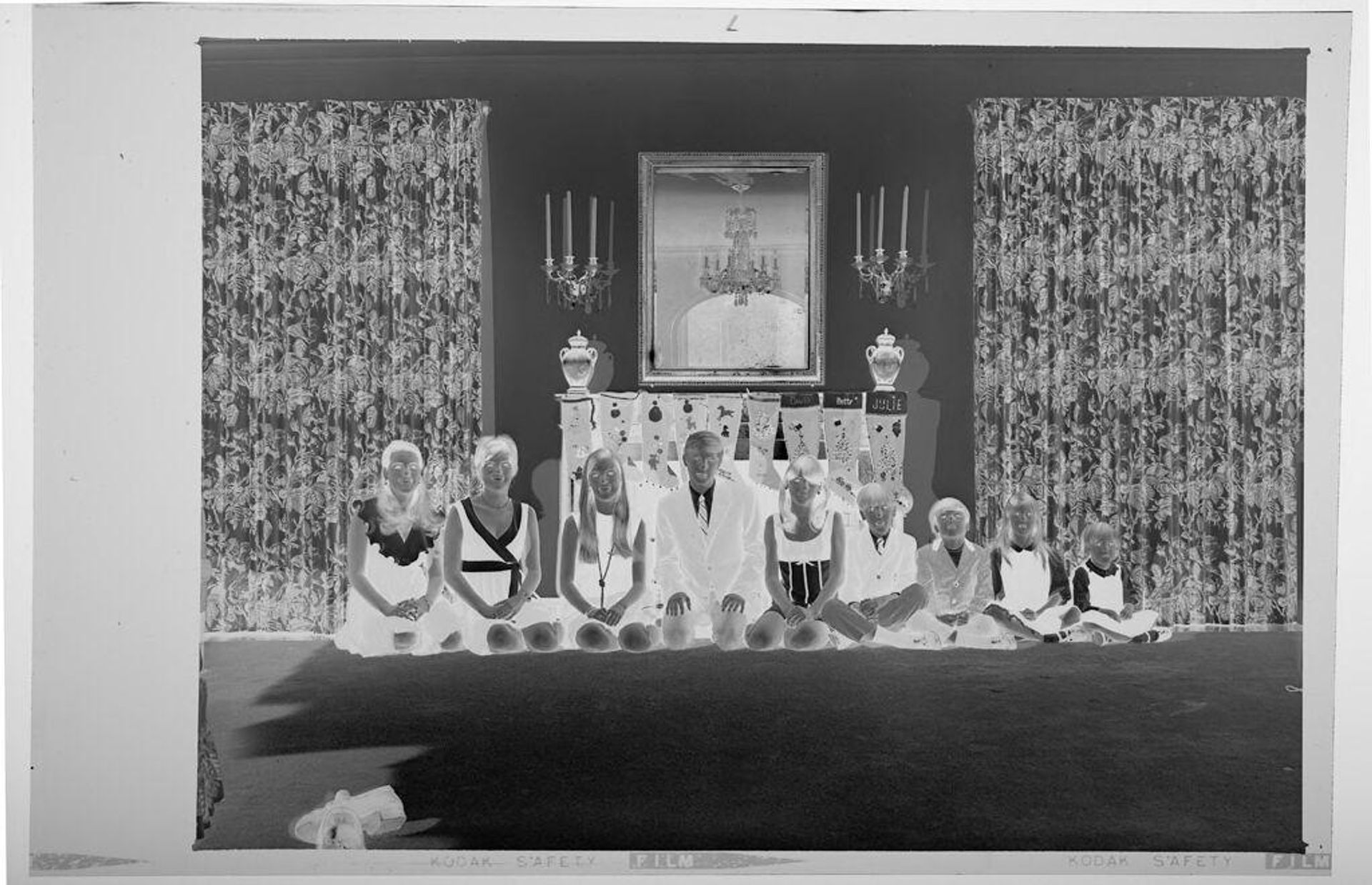 Untitled (nine children posed sitting in front of fireplace decorated for Christmas) by Martin Schweig
