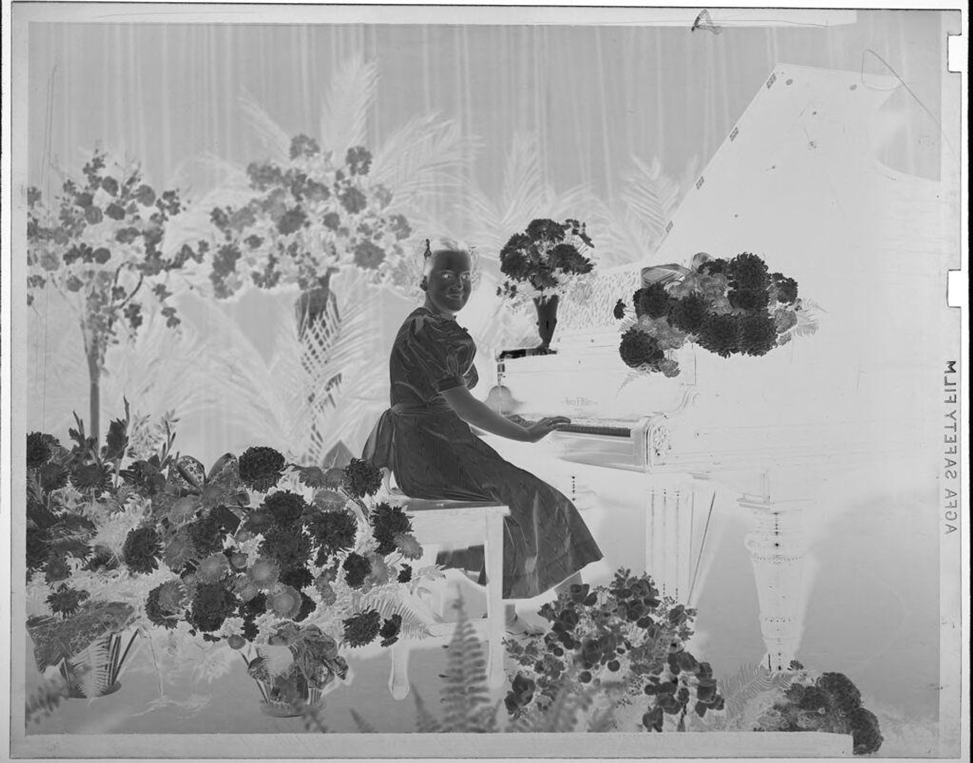 Untitled (girl posed sitting at piano surrounded by flowers) by Martin Schweig