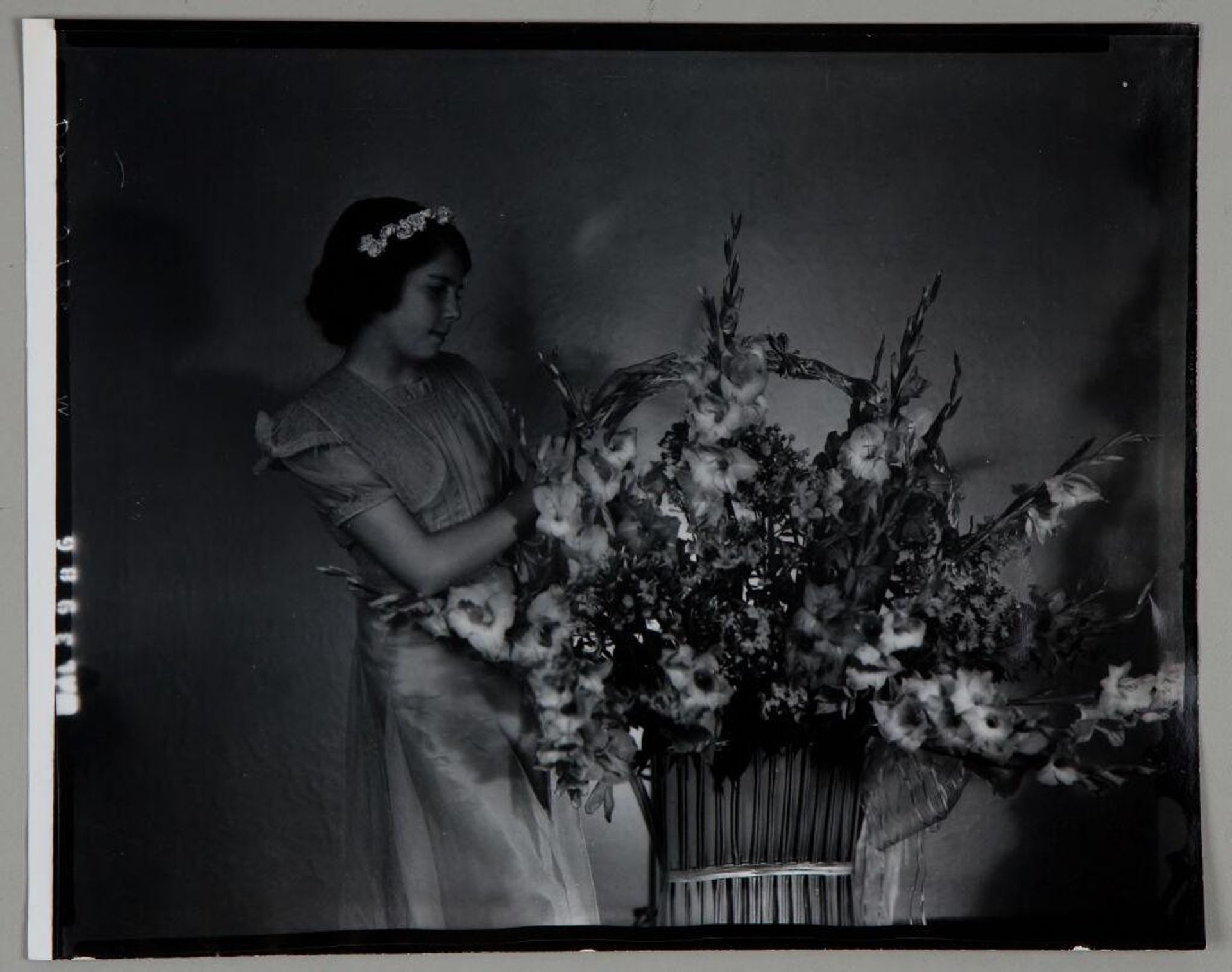 Untitled (girl with flowers in hair stading by large bouquet of flowers) by Paul Gittings