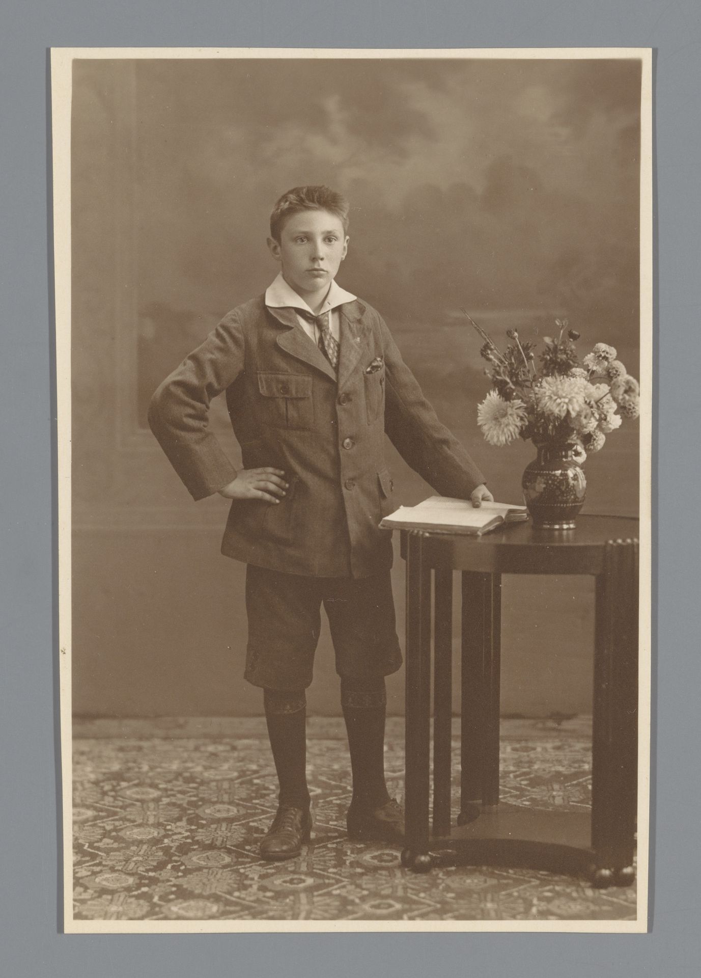 Studioportret van een onbekende jongen naast een tafel by Machiel Hendricus Laddé