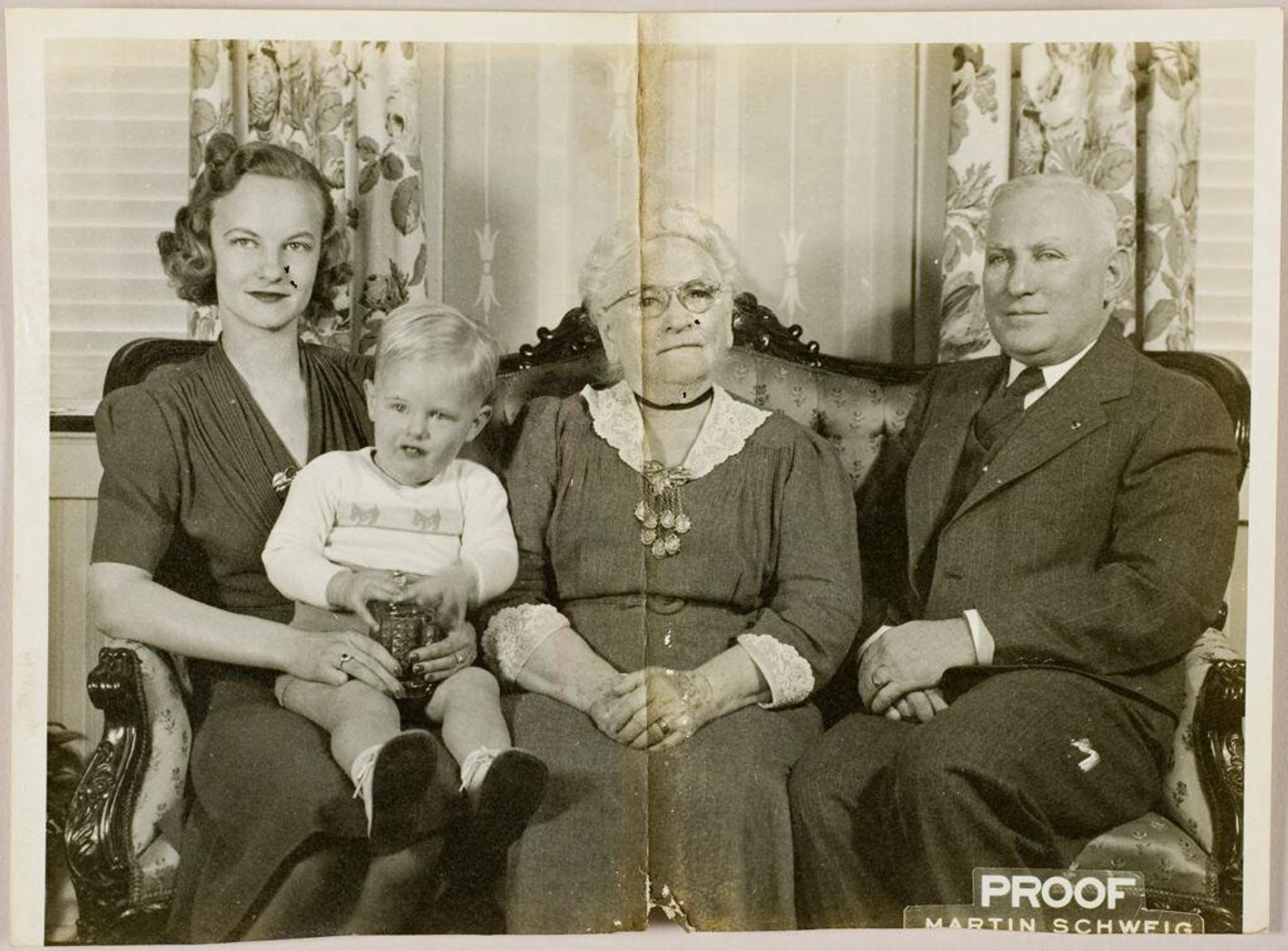 Untitled (older couple posed sitting on couch with younger woman and small boy) by Martin Schweig