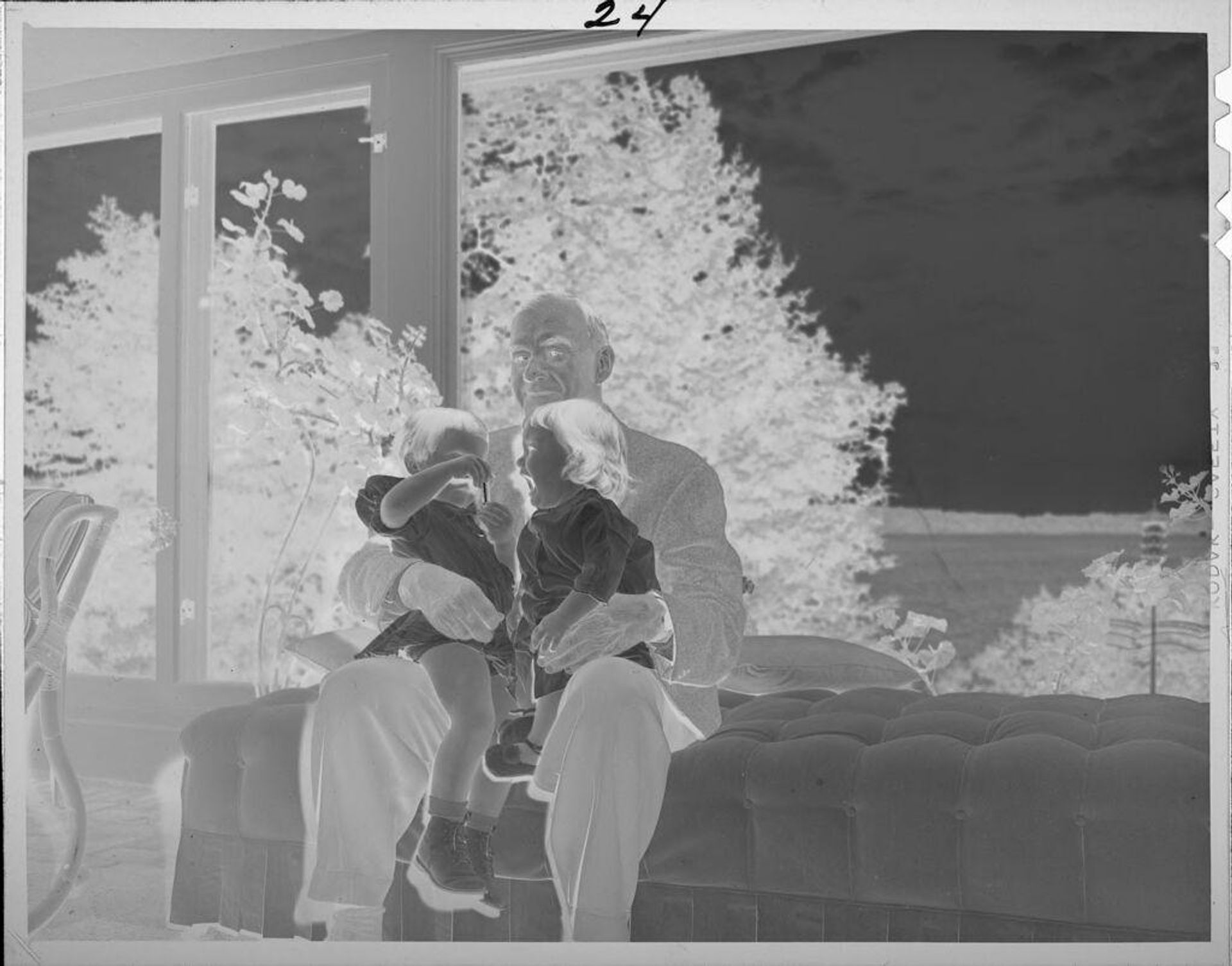 Untitled (older man, possibly grandfather, with two children on lap on couch) by Lucian and Mary Brown