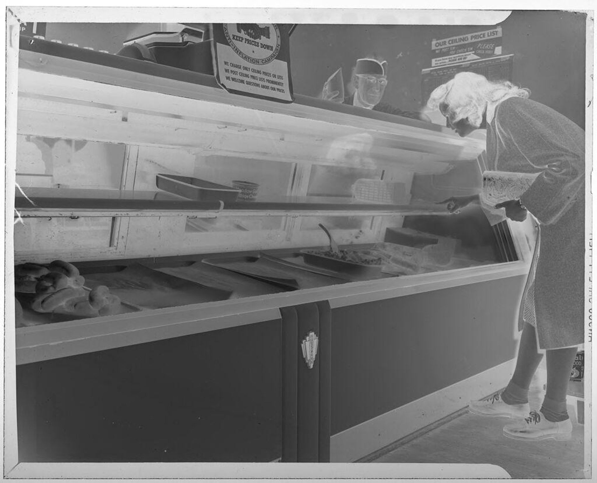 Untitled (woman choosing meat from almost-empty meat display) by Jack Gould