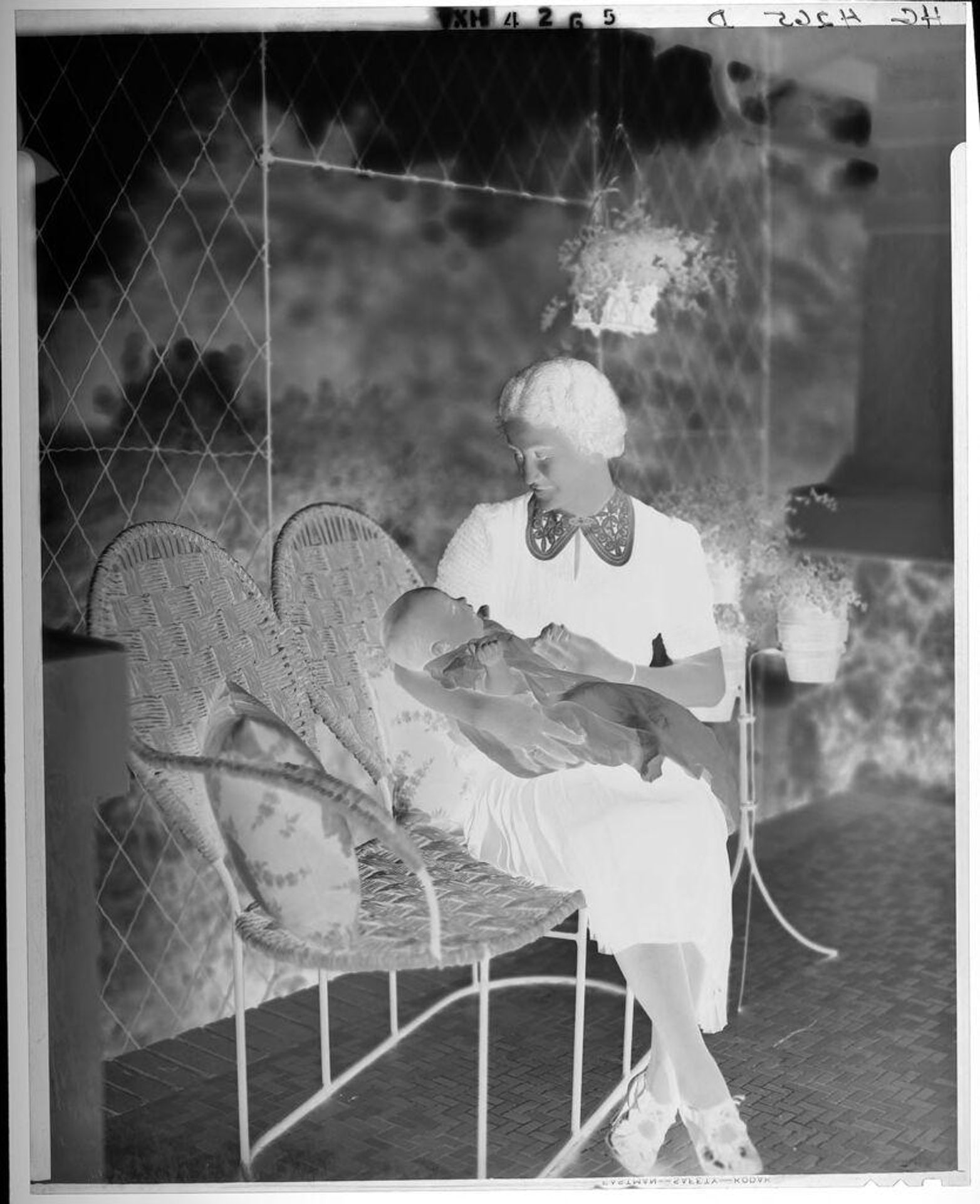 Untitled (woman seated on wicker bench holding baby) by Paul Gittings