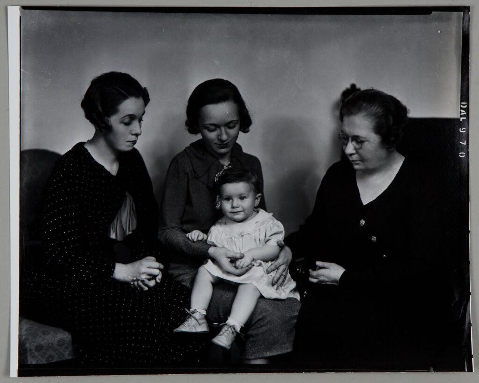 Untitled (three women seated and looking down at small child on central woman's lap) by Paul Gittings
