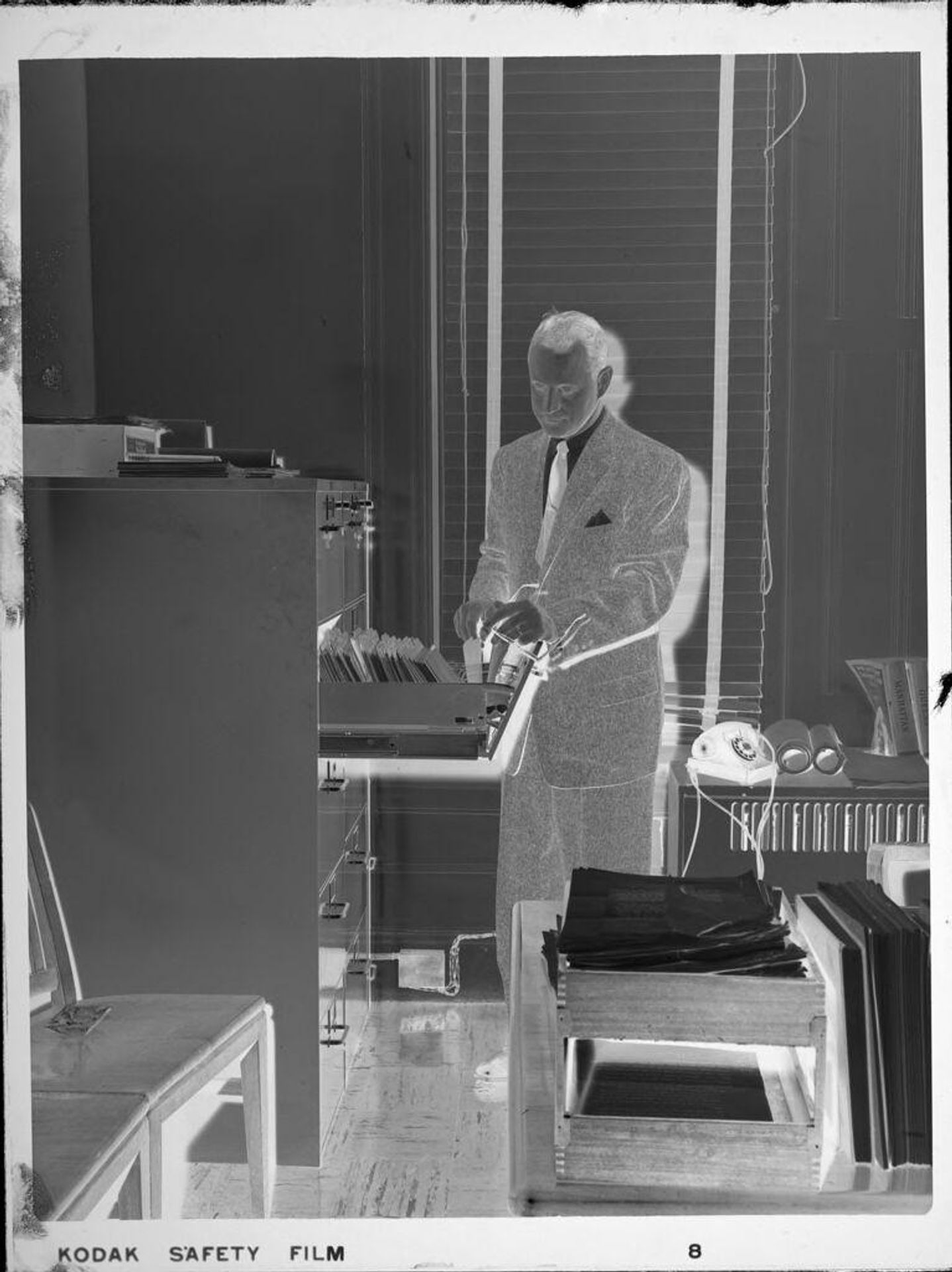 Untitled (man looking through files) by Peter James Studio