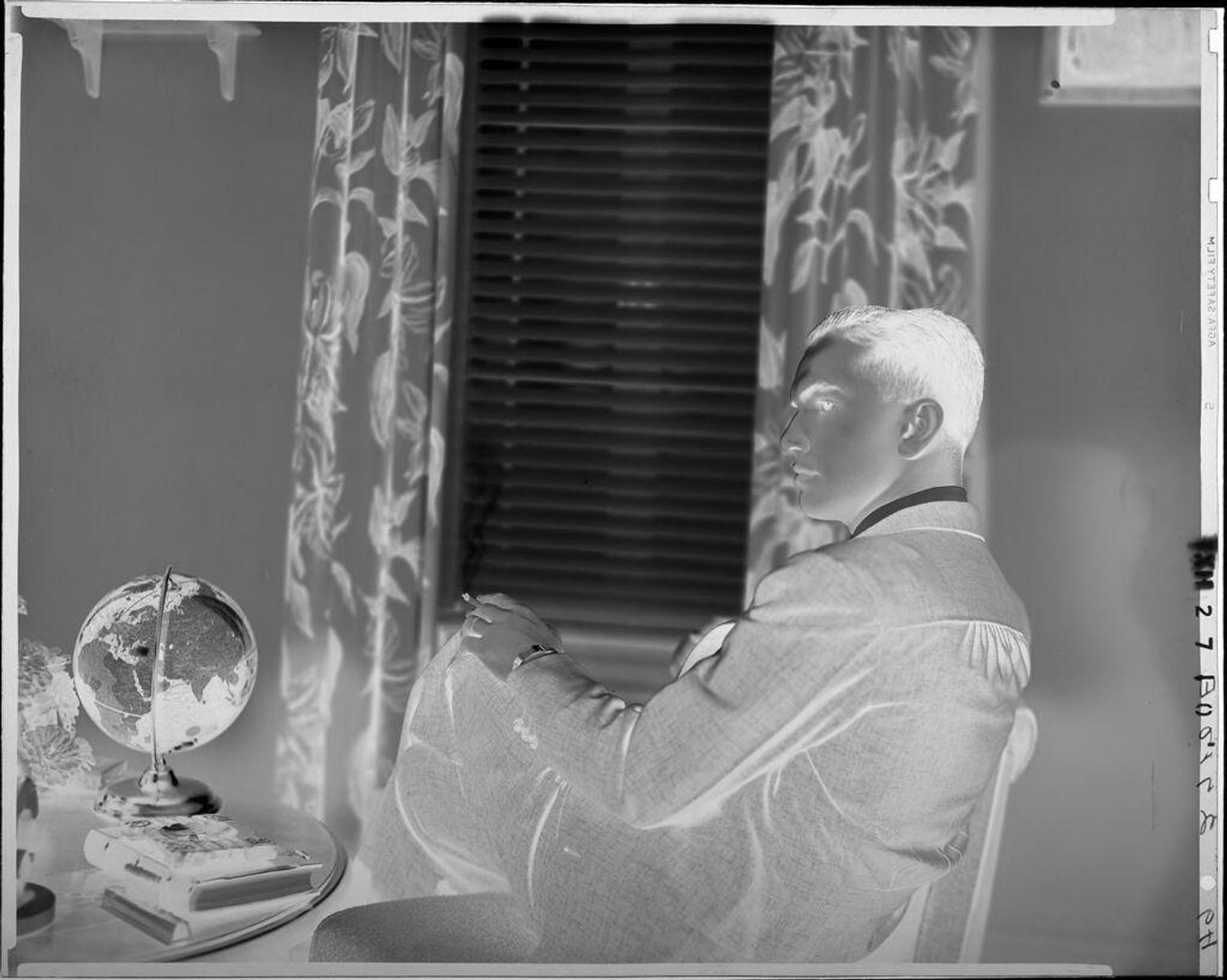 Untitled (young man holding cigarette seated next to globe) by Paul Gittings
