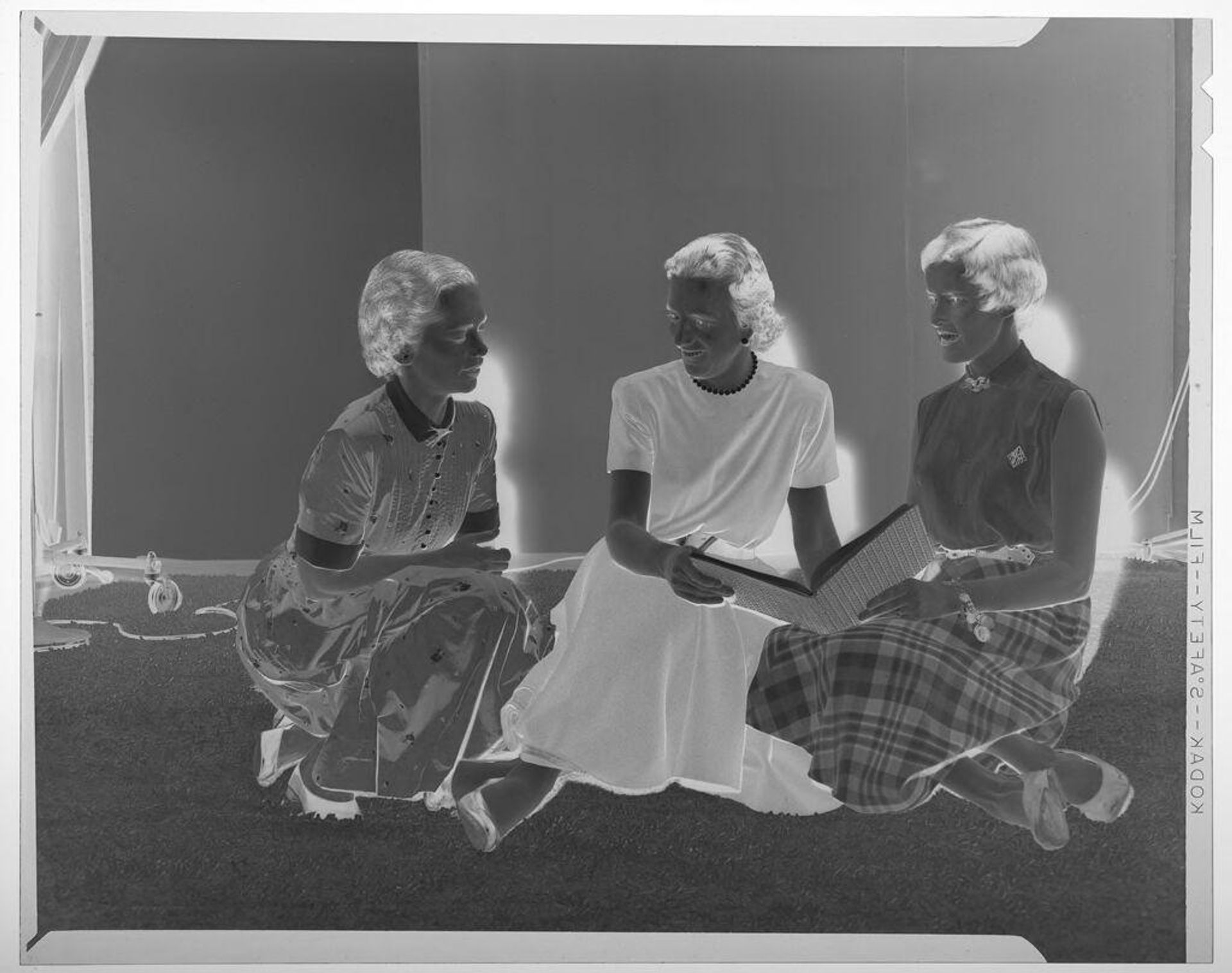 Untitled (three women sitting on floor and chatting while holding book) by Martin Schweig