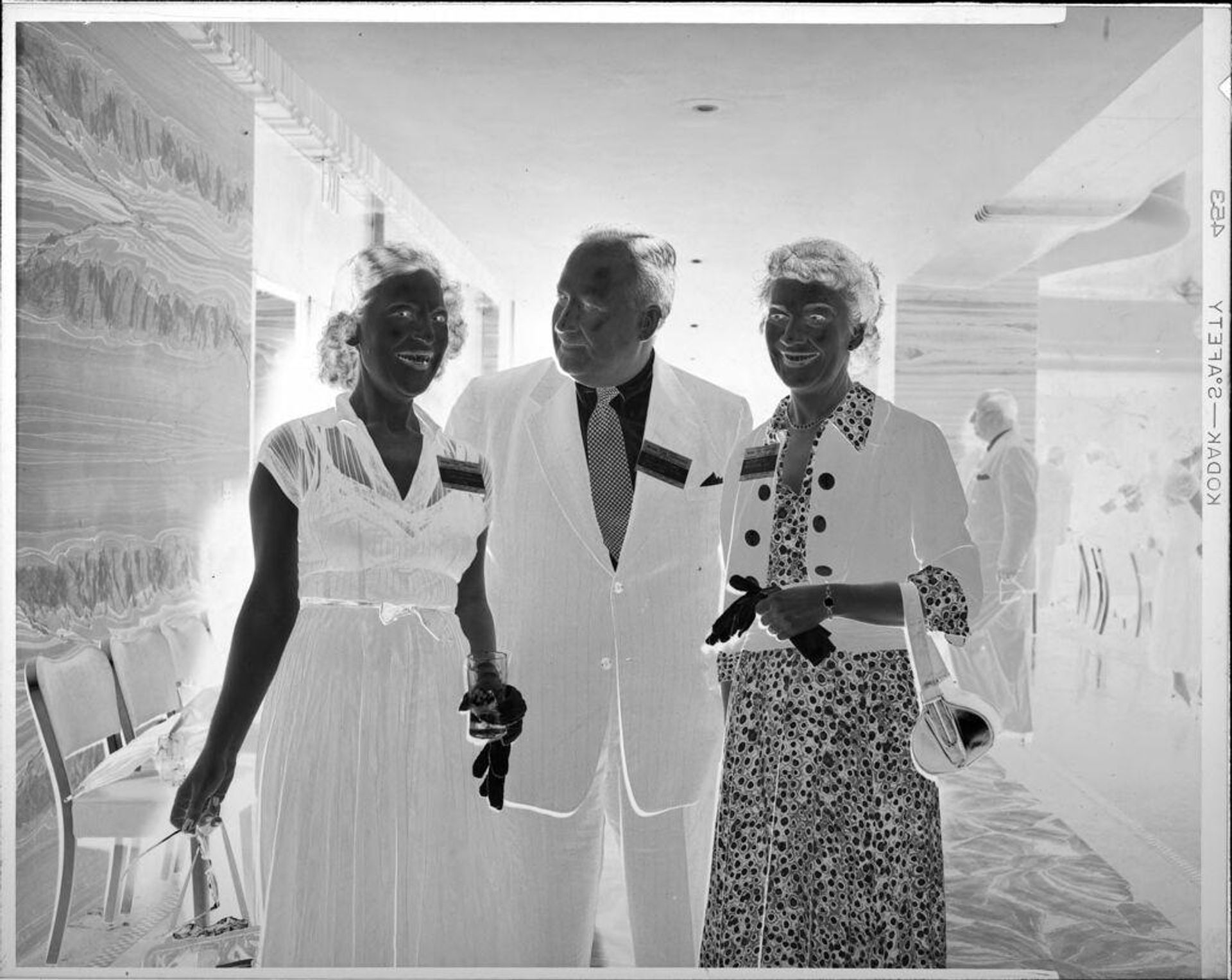 Untitled (man and two women standing at party) by Peter James Studio