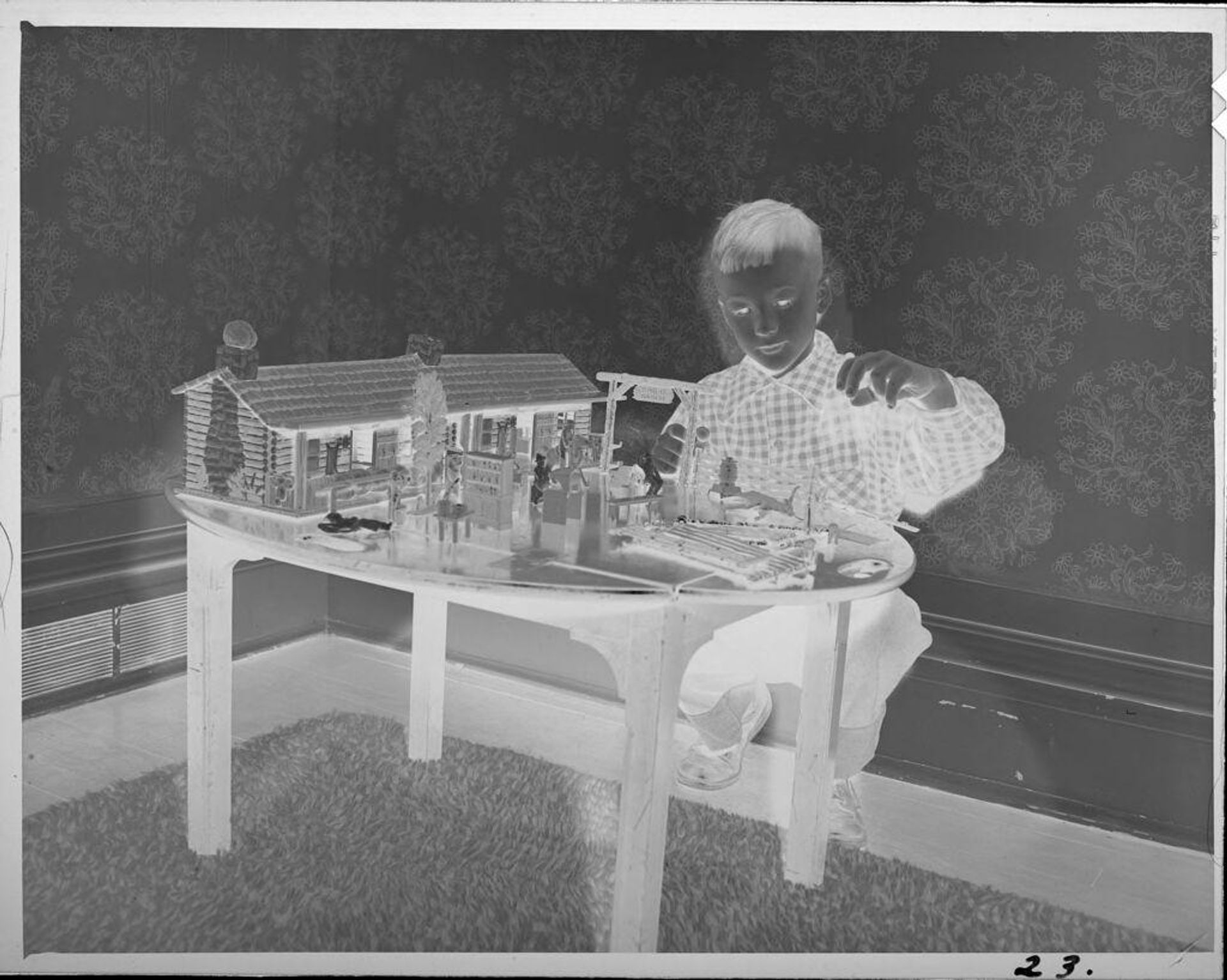 Untitled (boy playing with model ranch house) by Lucian and Mary Brown