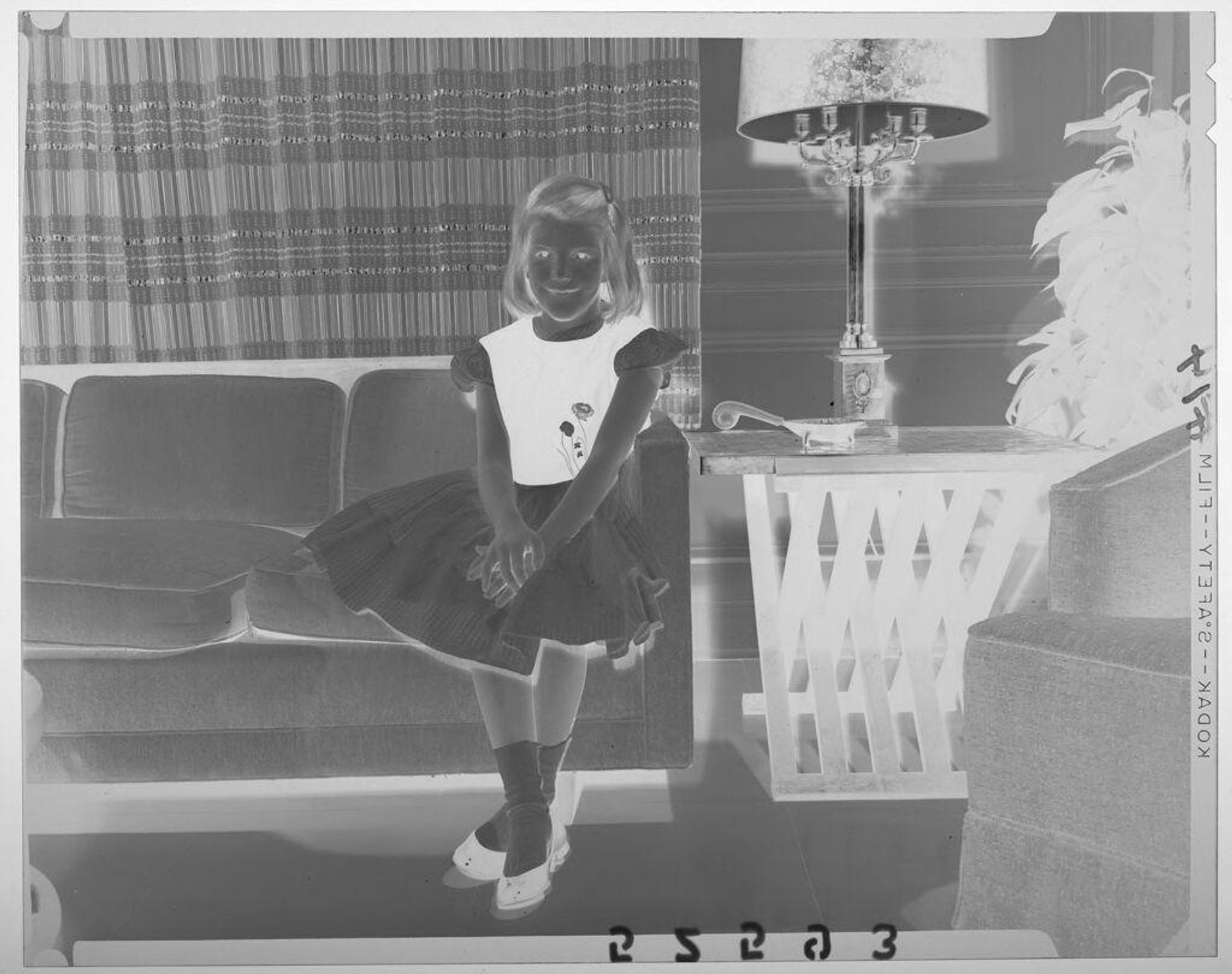 Untitled (young girl in dress posed sitting on living room couch) by Martin Schweig