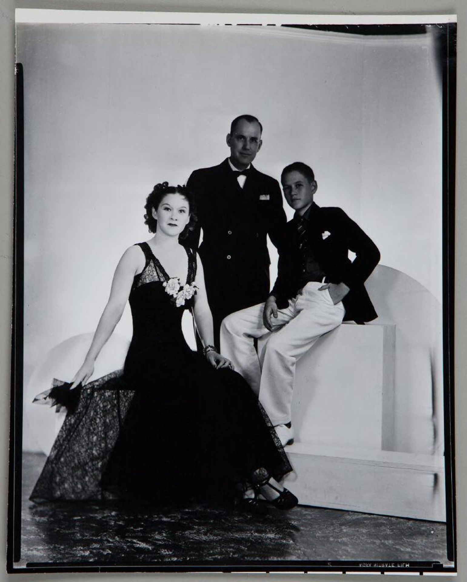 Untitled (portrait of man, woman, and boy in formal wear seated on geometrically shaped studio props) by Paul Gittings