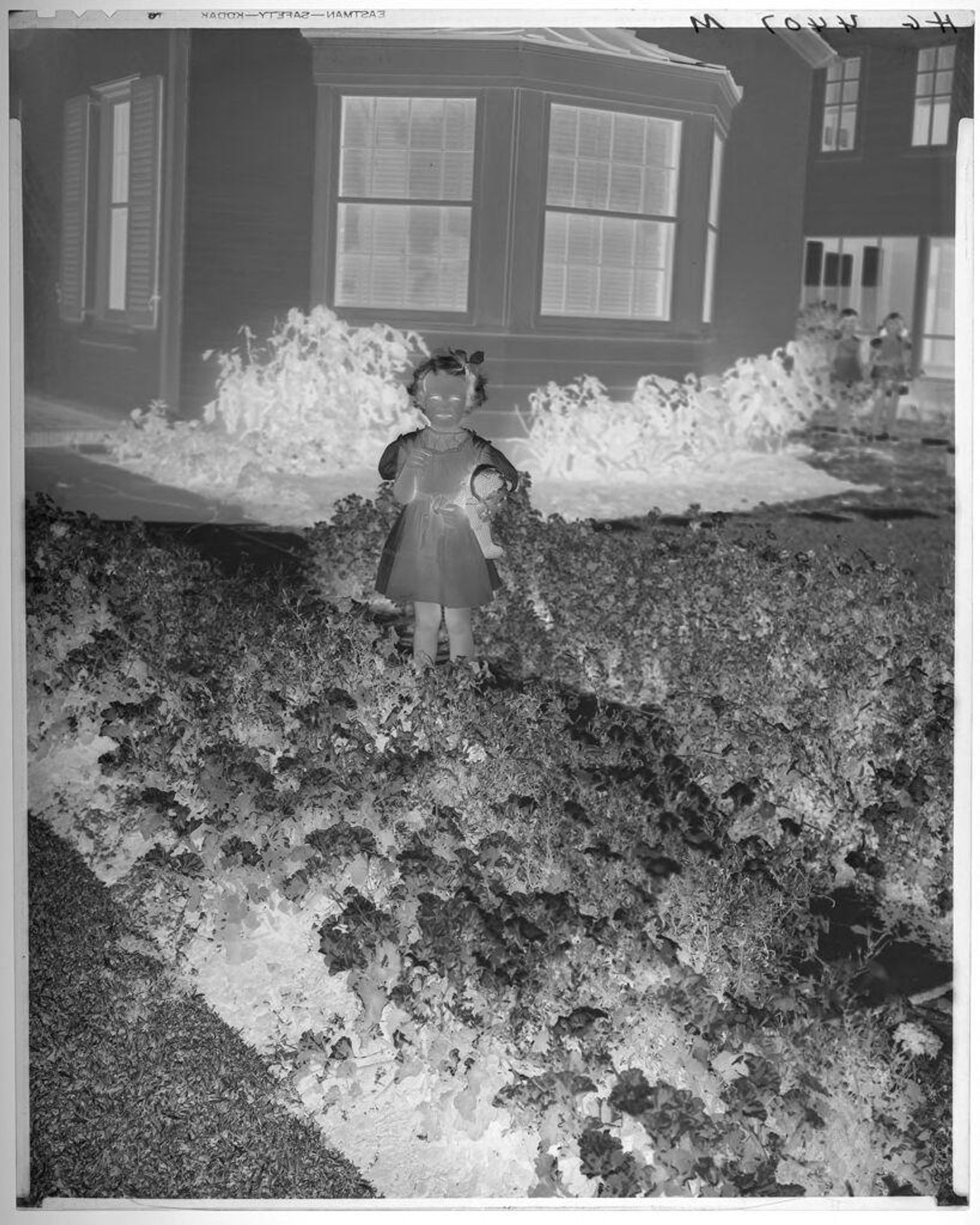 Untitled (portrait of little girl holding stuffed animal standing in front of house) by Paul Gittings