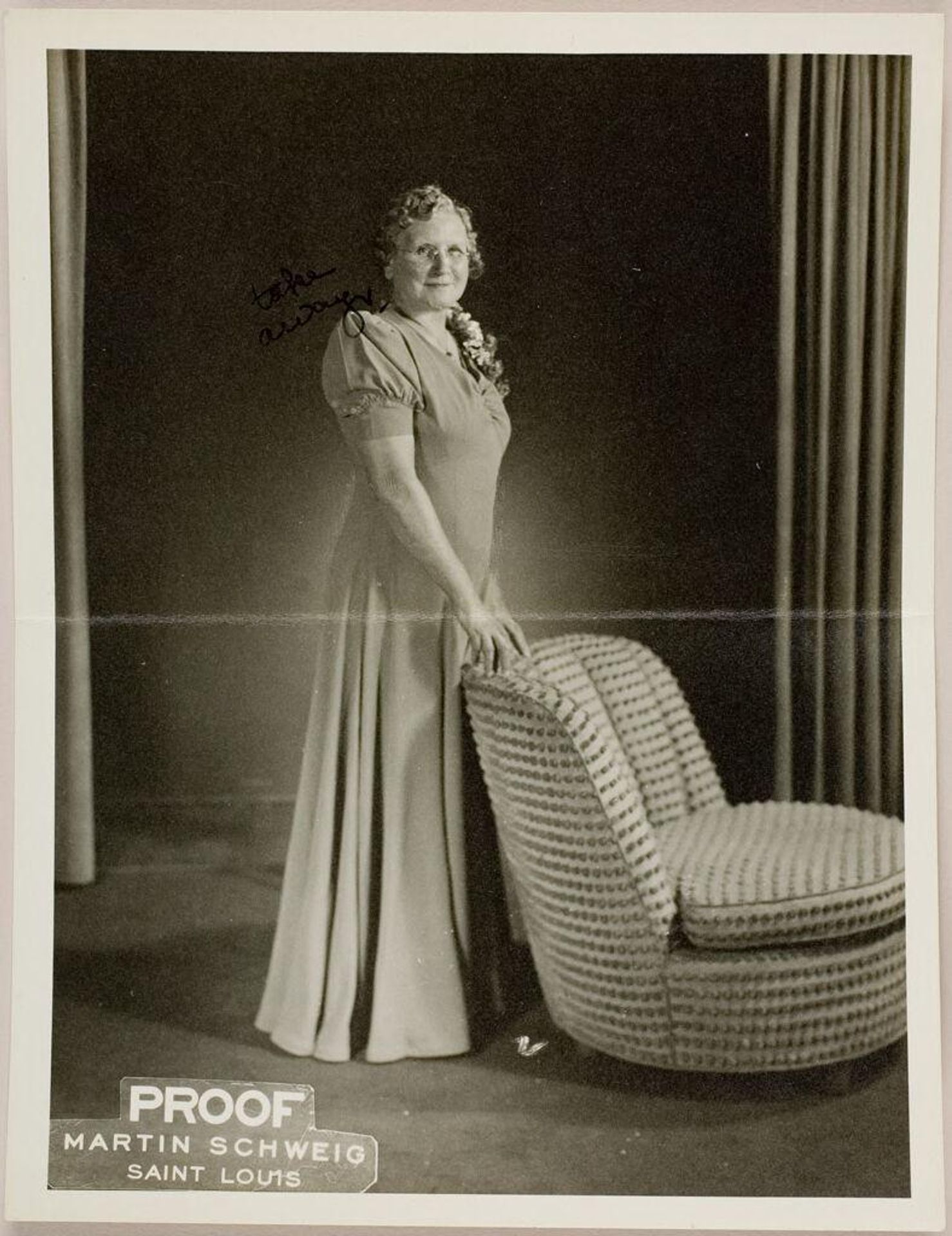 Untitled (studio portrait of middle-aged woman wearing glasses and dress posed standing next to chair) by Martin Schweig