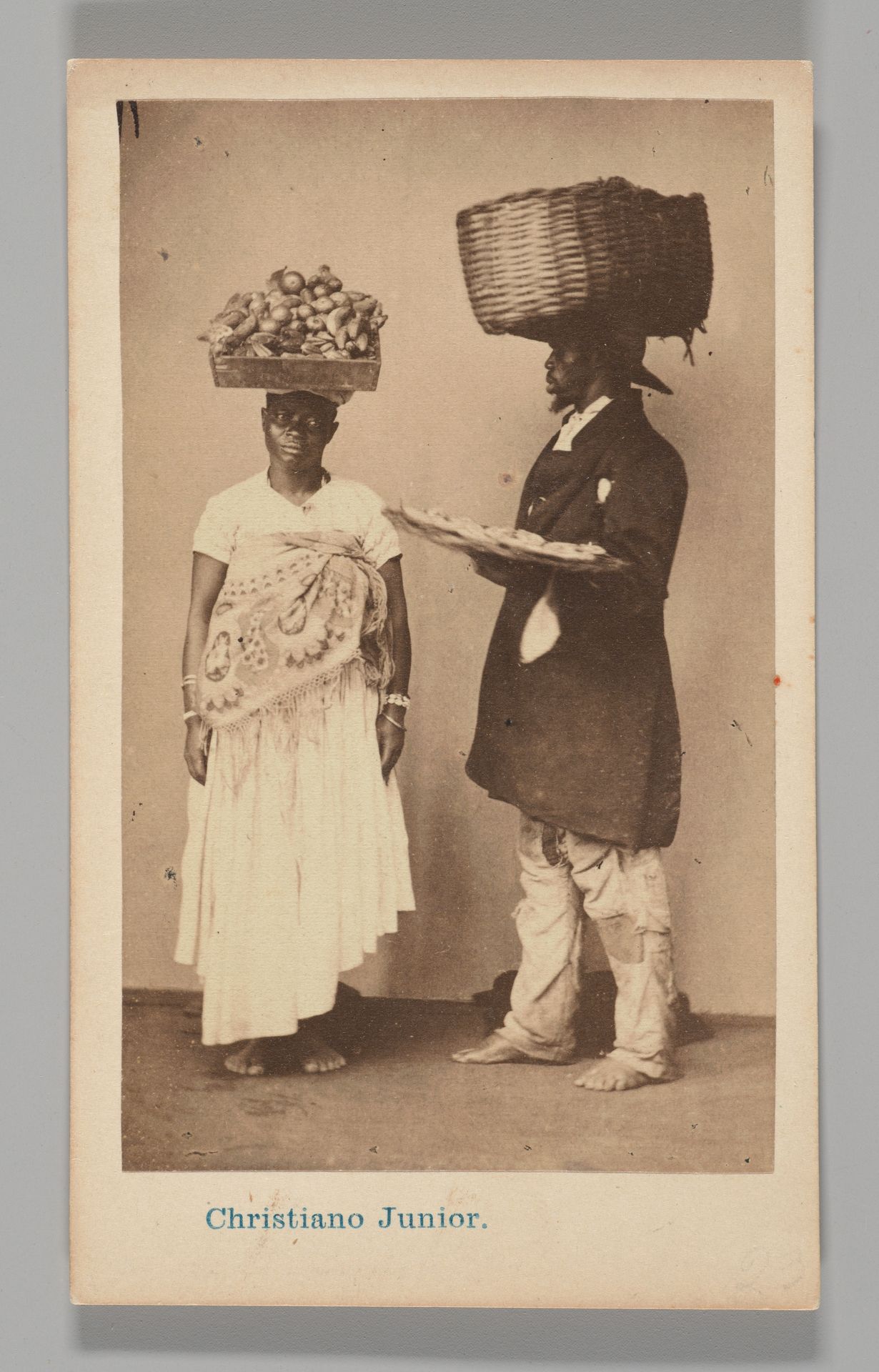 [Studio Portrait: Female and Male Street Vendors with Baskets on Head, Brazil] by Christiano Junior