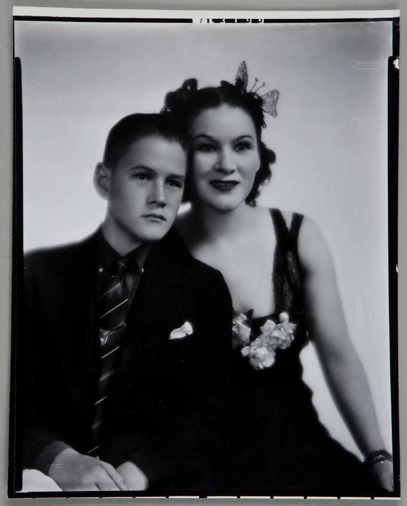 Untitled (woman in formal dress with flowers on chest seated with young man in suit) by Paul Gittings