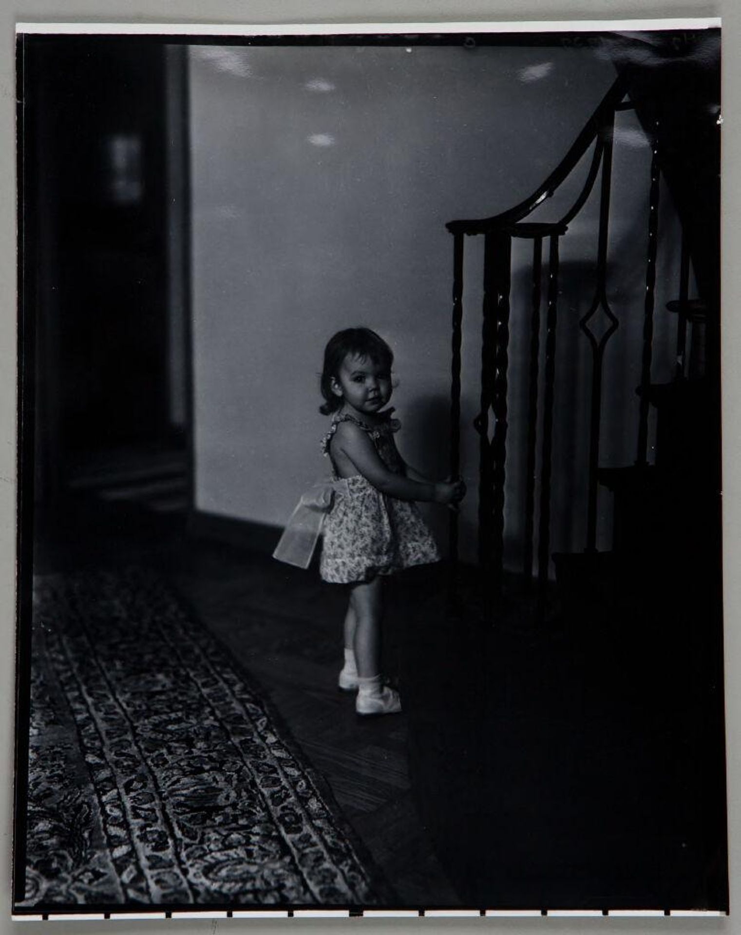 Untitled (little girl in sleeveless dress standing at base of staircase) by Paul Gittings