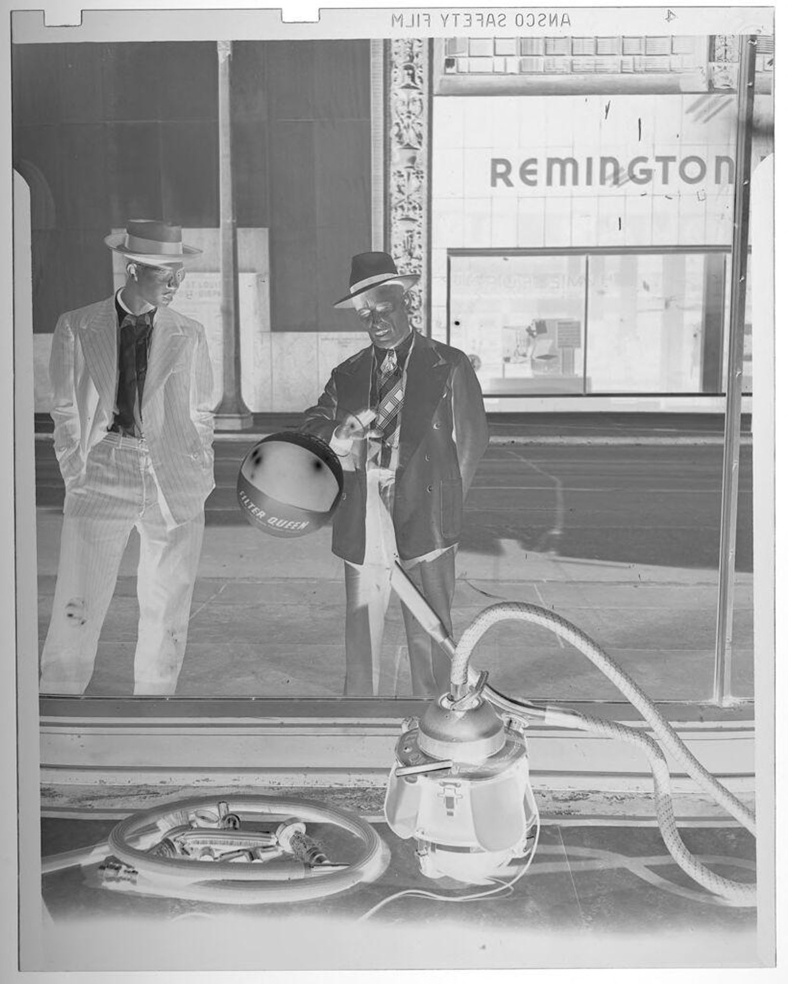 Untitled (men looking at vacuum demonstration in shop window) by Jack Gould