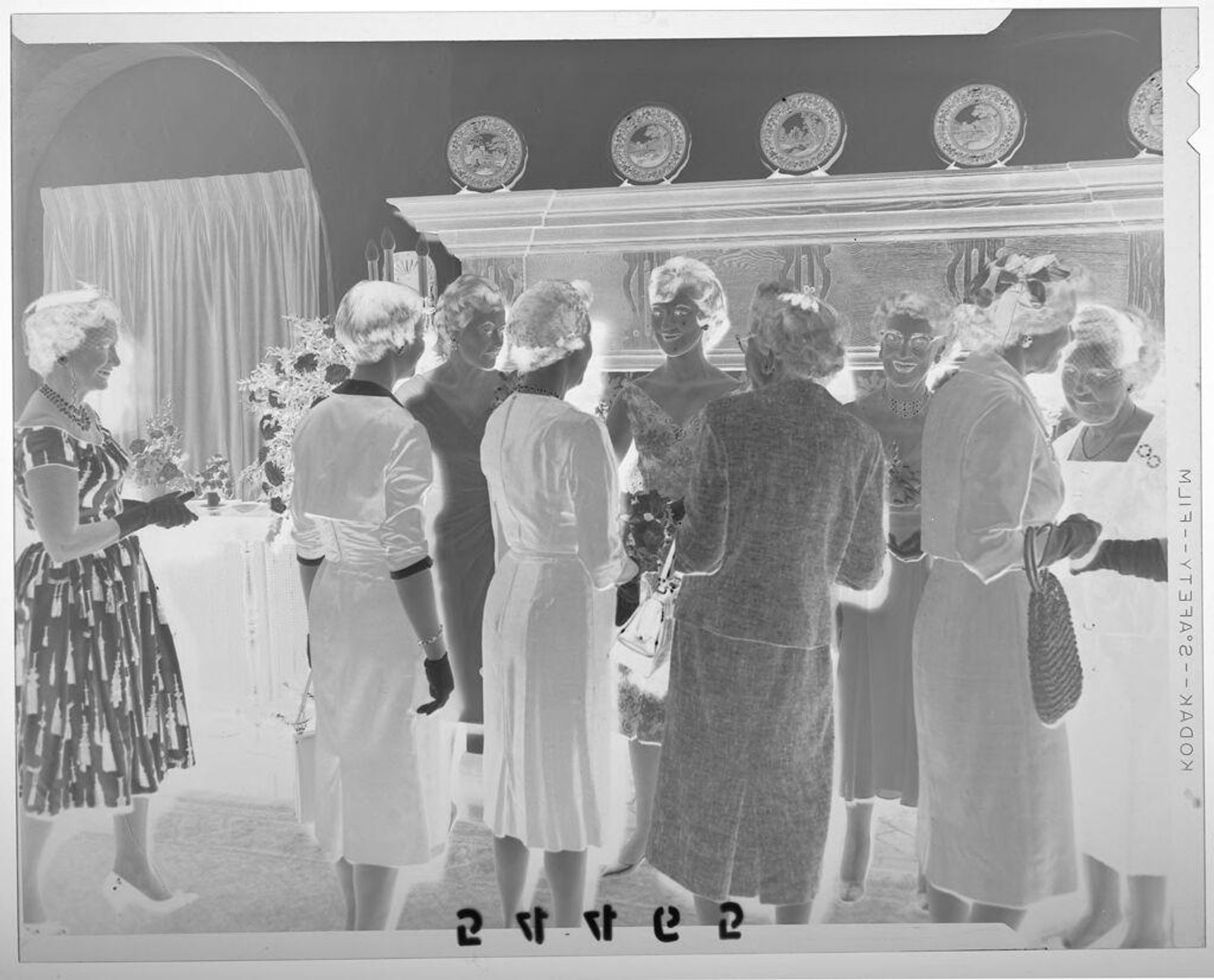 Untitled (young woman greeting guests in front of fireplace at debutante party) by Martin Schweig